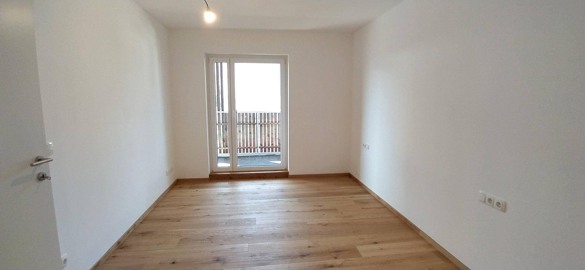 Helles Schlafzimmer mit Holzboden und direktem Zugang zu einem privaten Balkon.