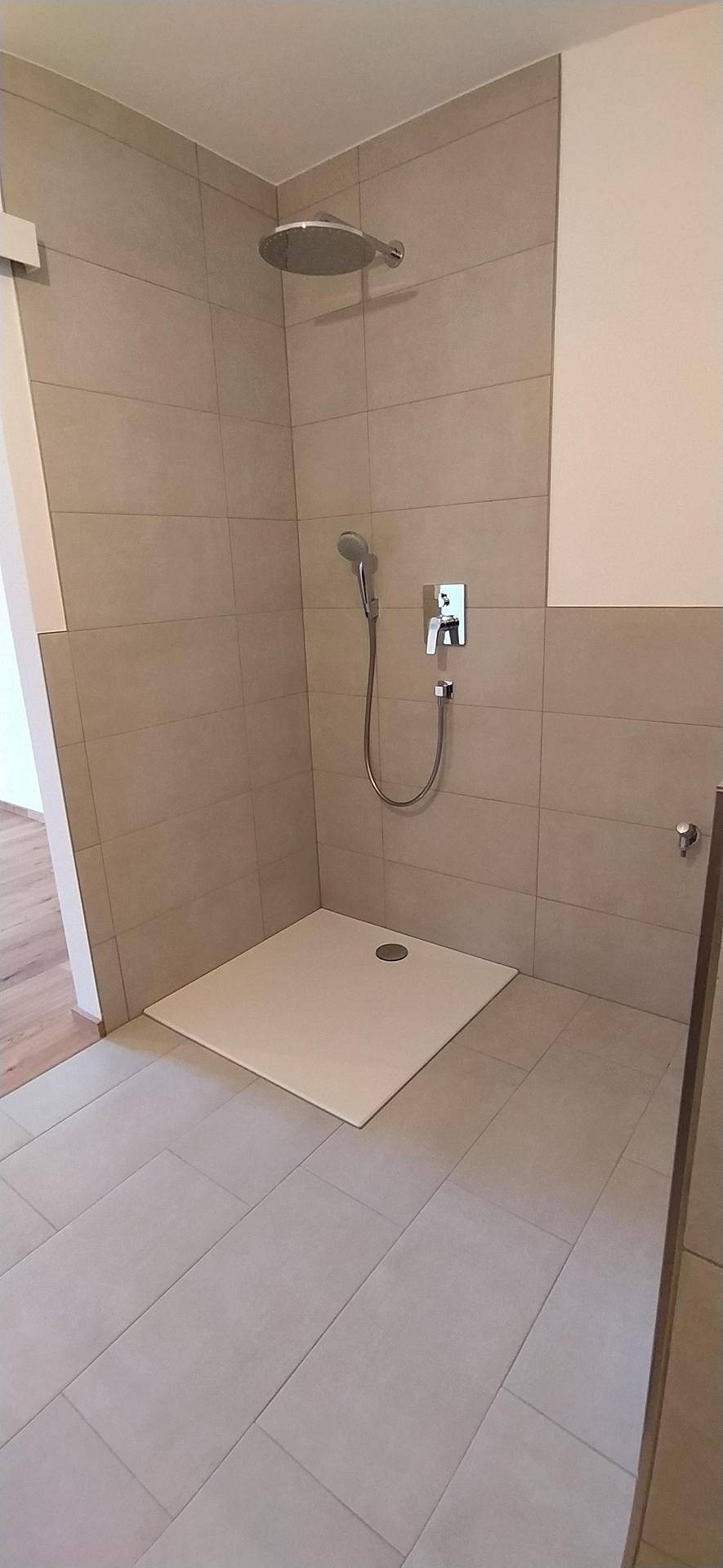 Geräumige begehbare Dusche mit Regenduschkopf und modernen grauen Fliesen.