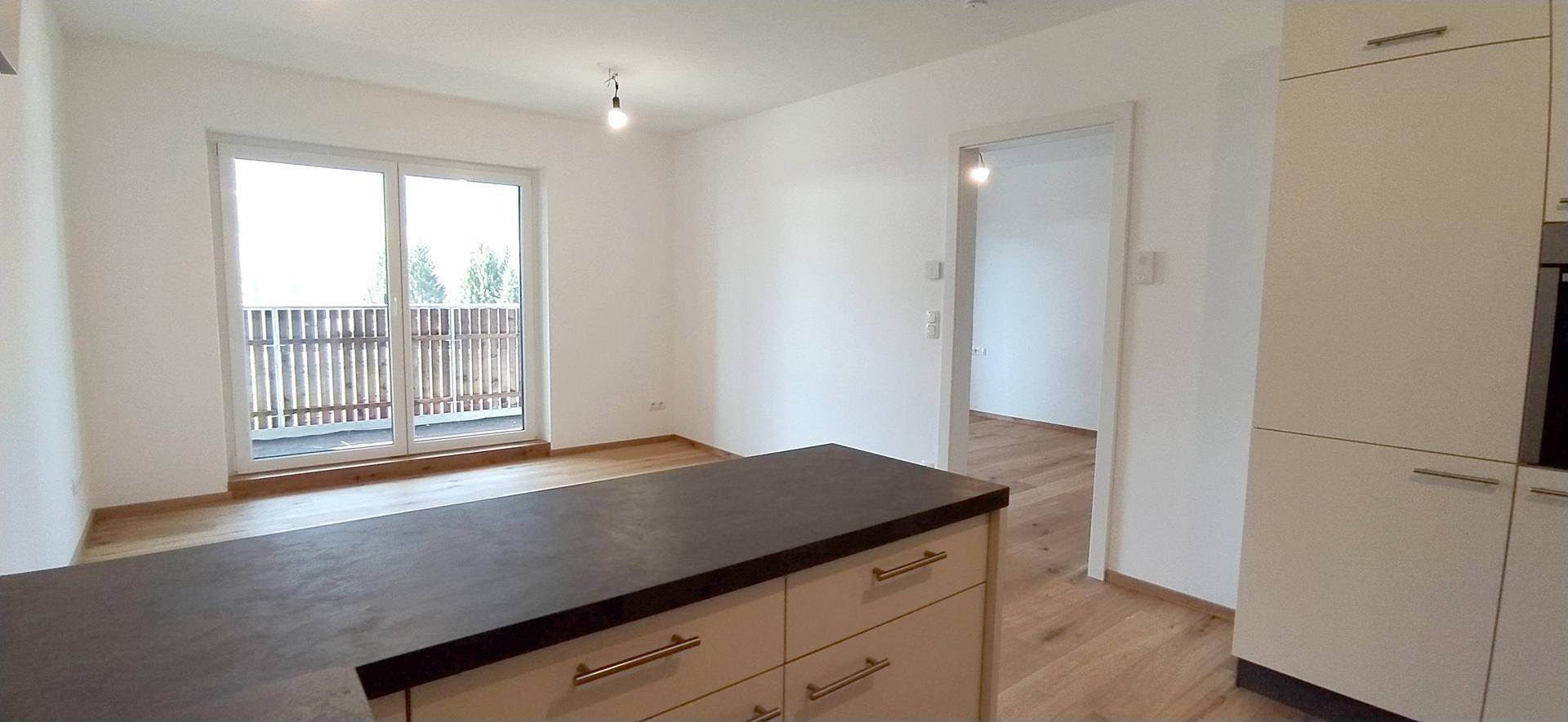 Heller Wohnbereich mit Holzboden und Zugang zu einem Balkon, ideal für offenes Wohnen.