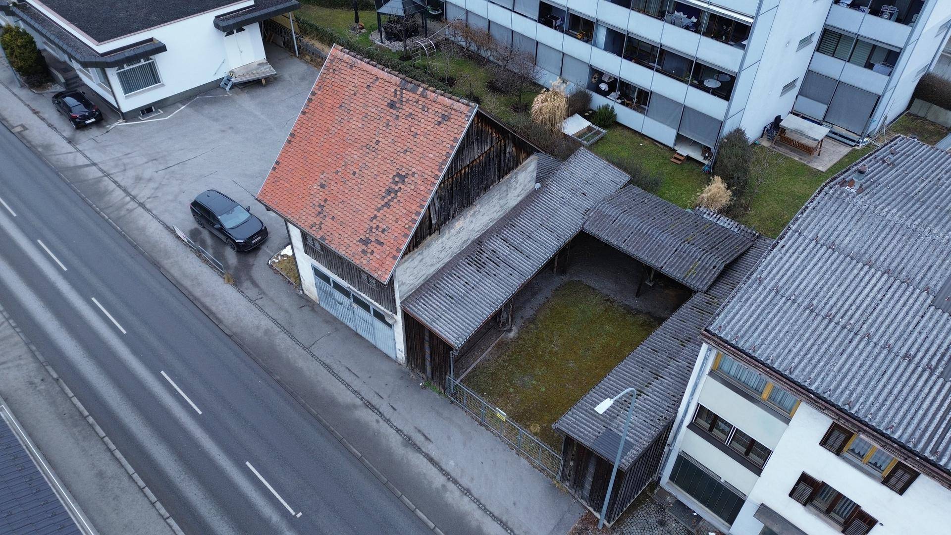 Vogelperspektive des Anwesens mit einem alten Haus, einem überdachten Hof und der angrenzenden Straße.