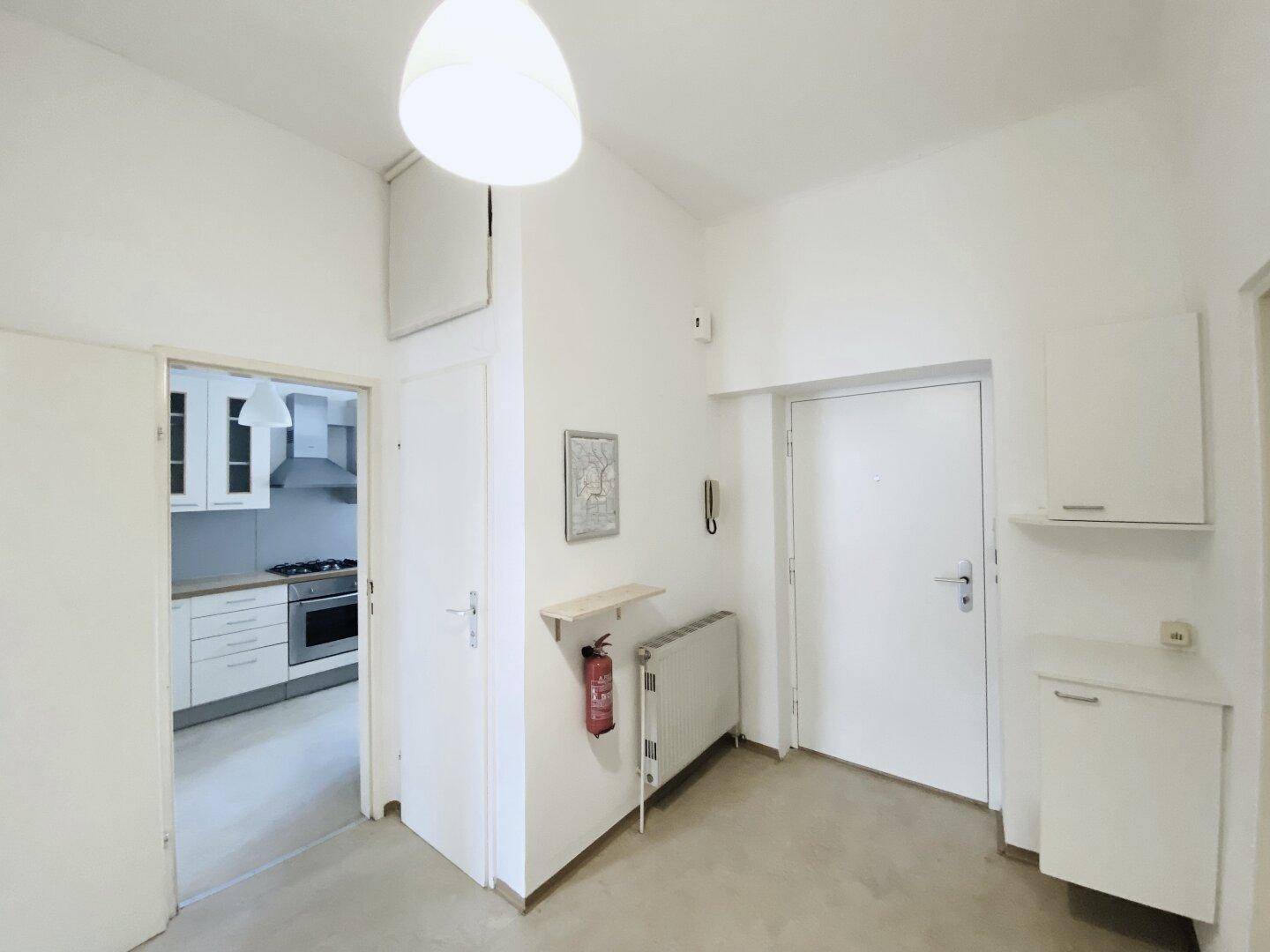 Heller Flur mit Zugang zur Küche und einem Heizkörper an der Wand.