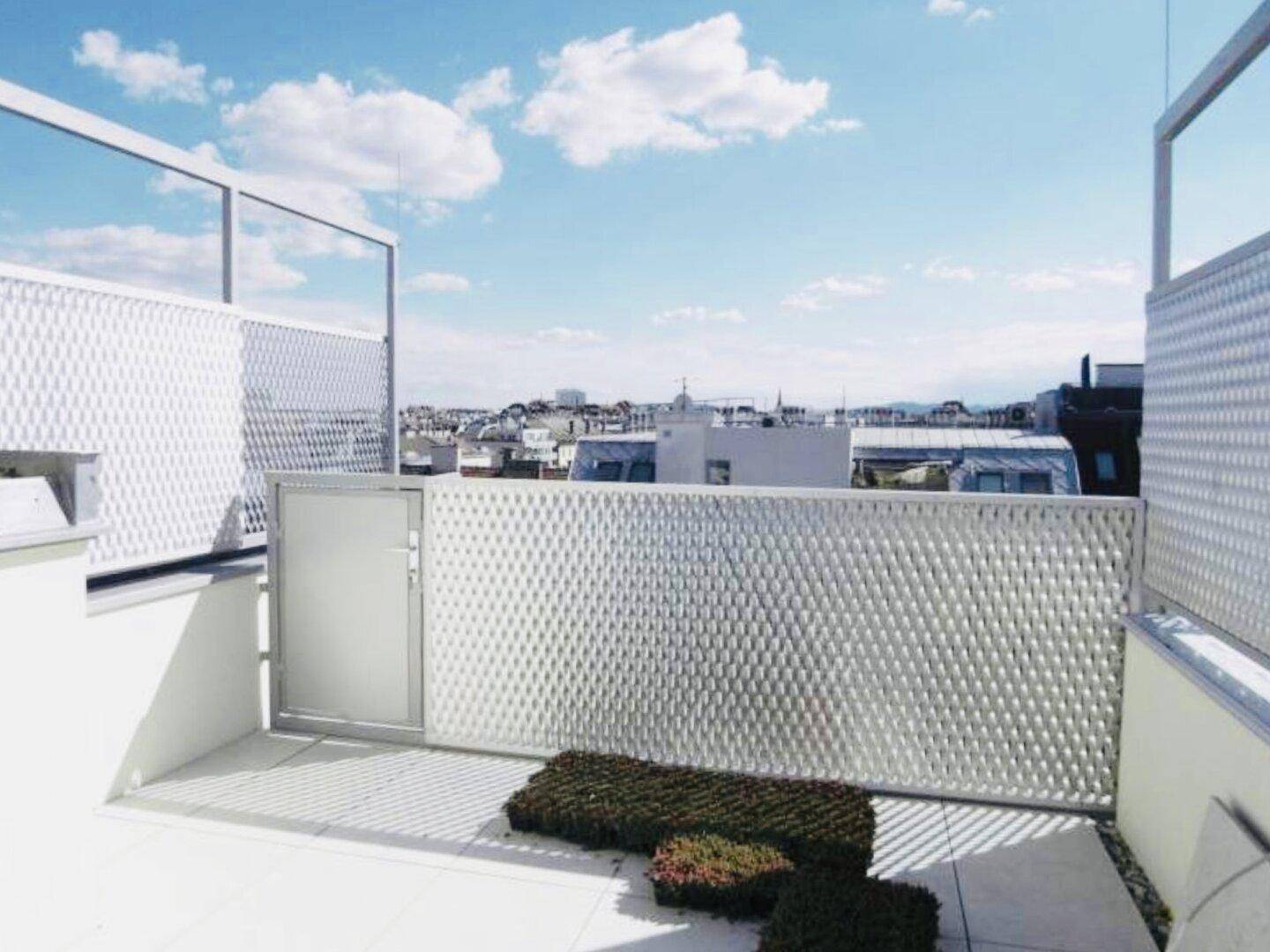 Moderne Dachterrasse mit dekorativen Metallzäunen und Blick über die Stadt.