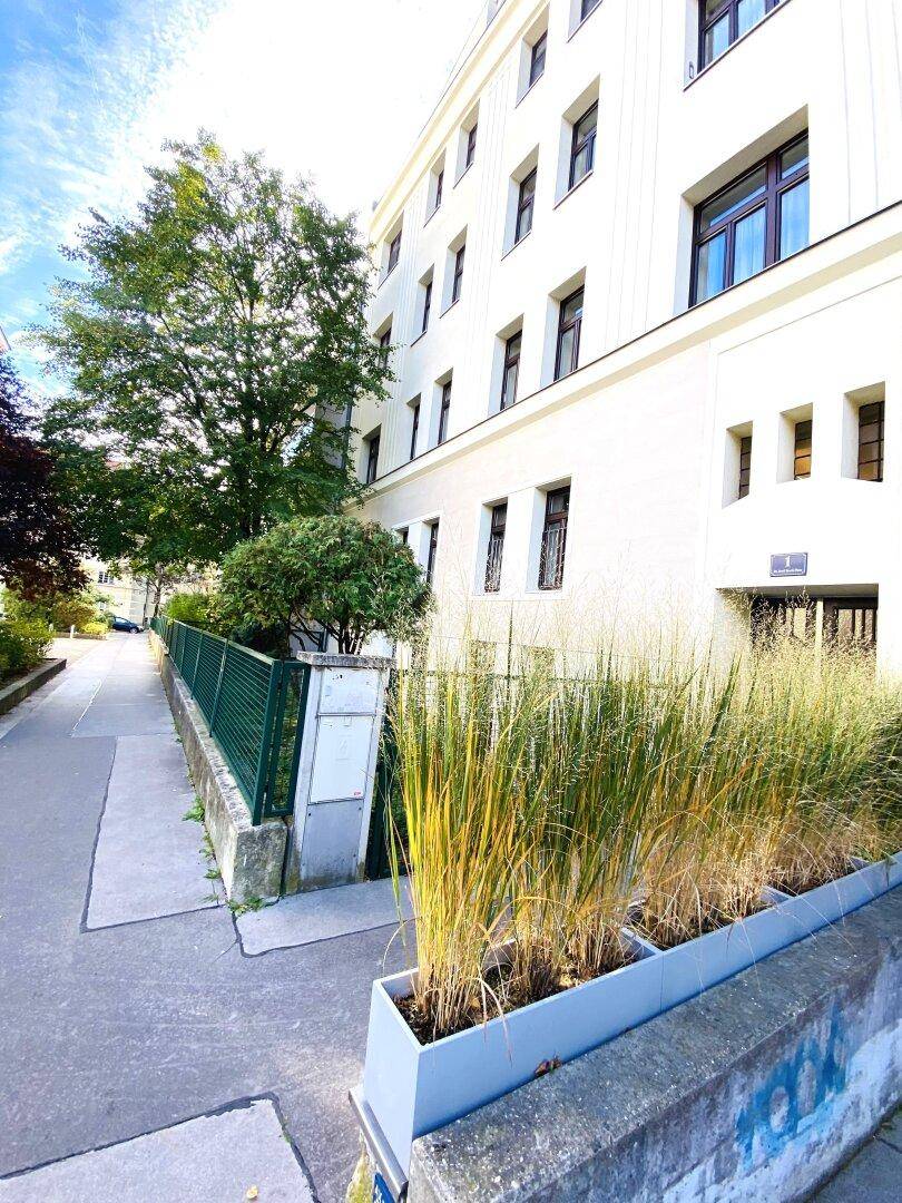 Fassade eines modernen Wohngebäudes mit vielen Fenstern und Grünflächen.