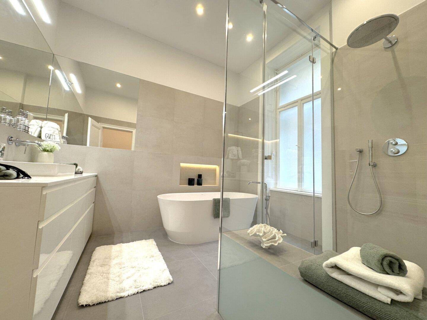 Modernes Badezimmer mit freistehender Badewanne, großer begehbarer Dusche und Fenster.