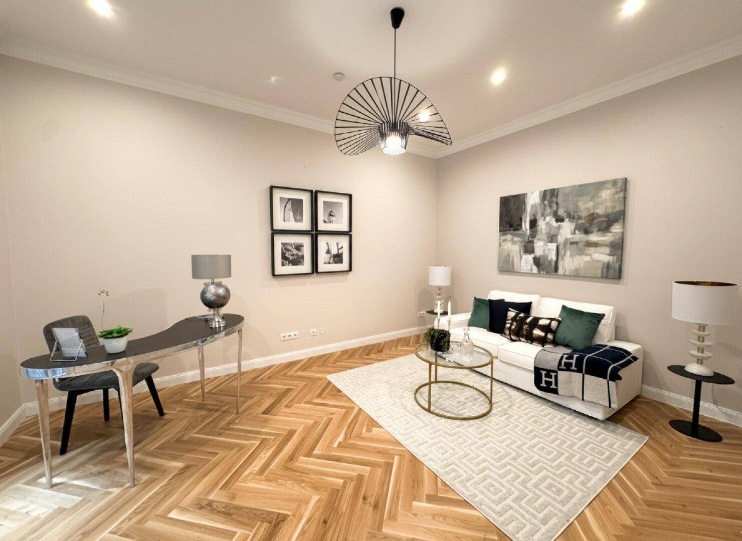 Modernes Arbeitszimmer mit Schreibtisch, bequemer Couch und Fischgrätparkettboden.