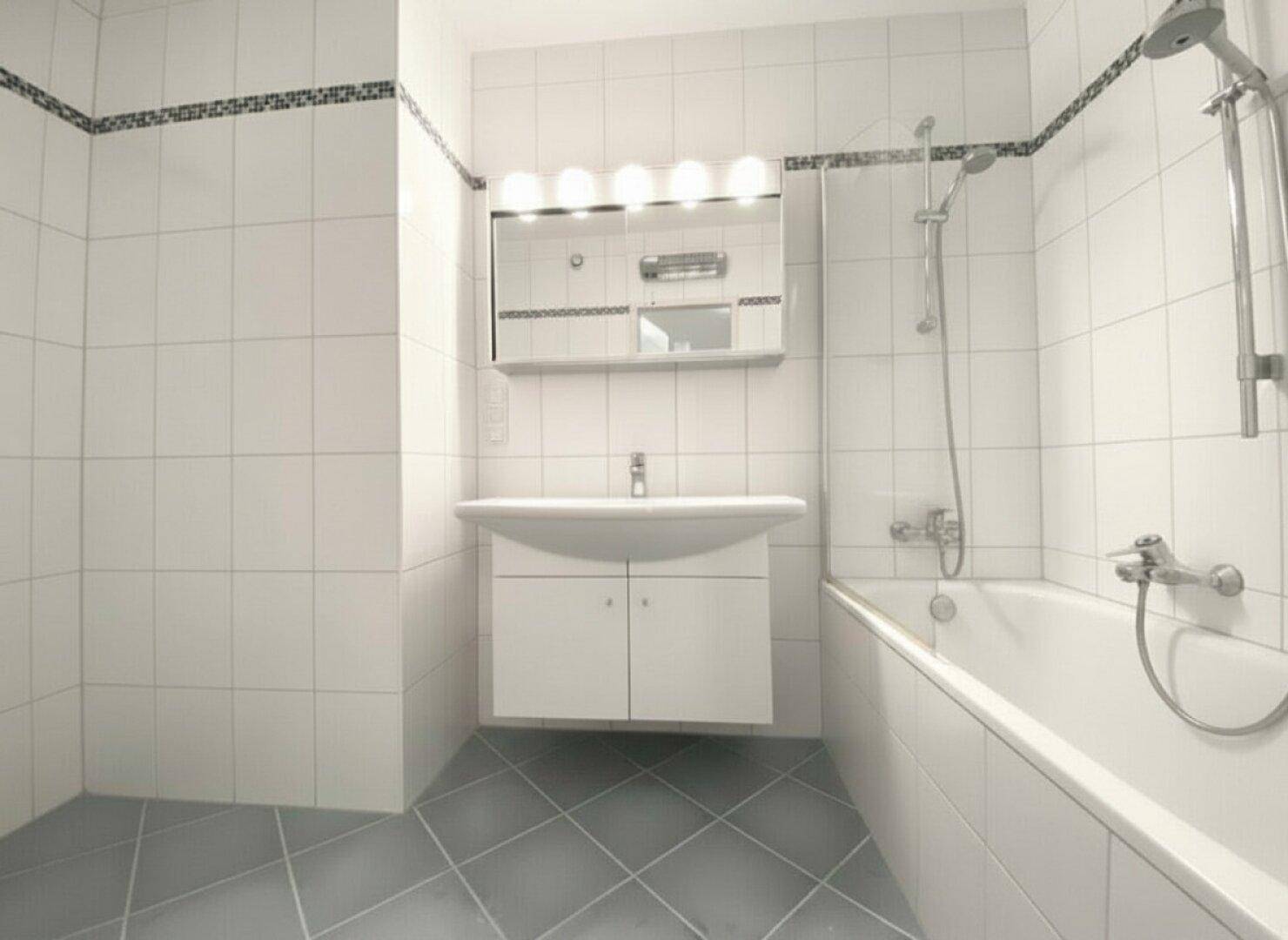 Gefliestes Badezimmer mit Badewanne, Duschvorrichtung, Waschbecken und Spiegelschrank.