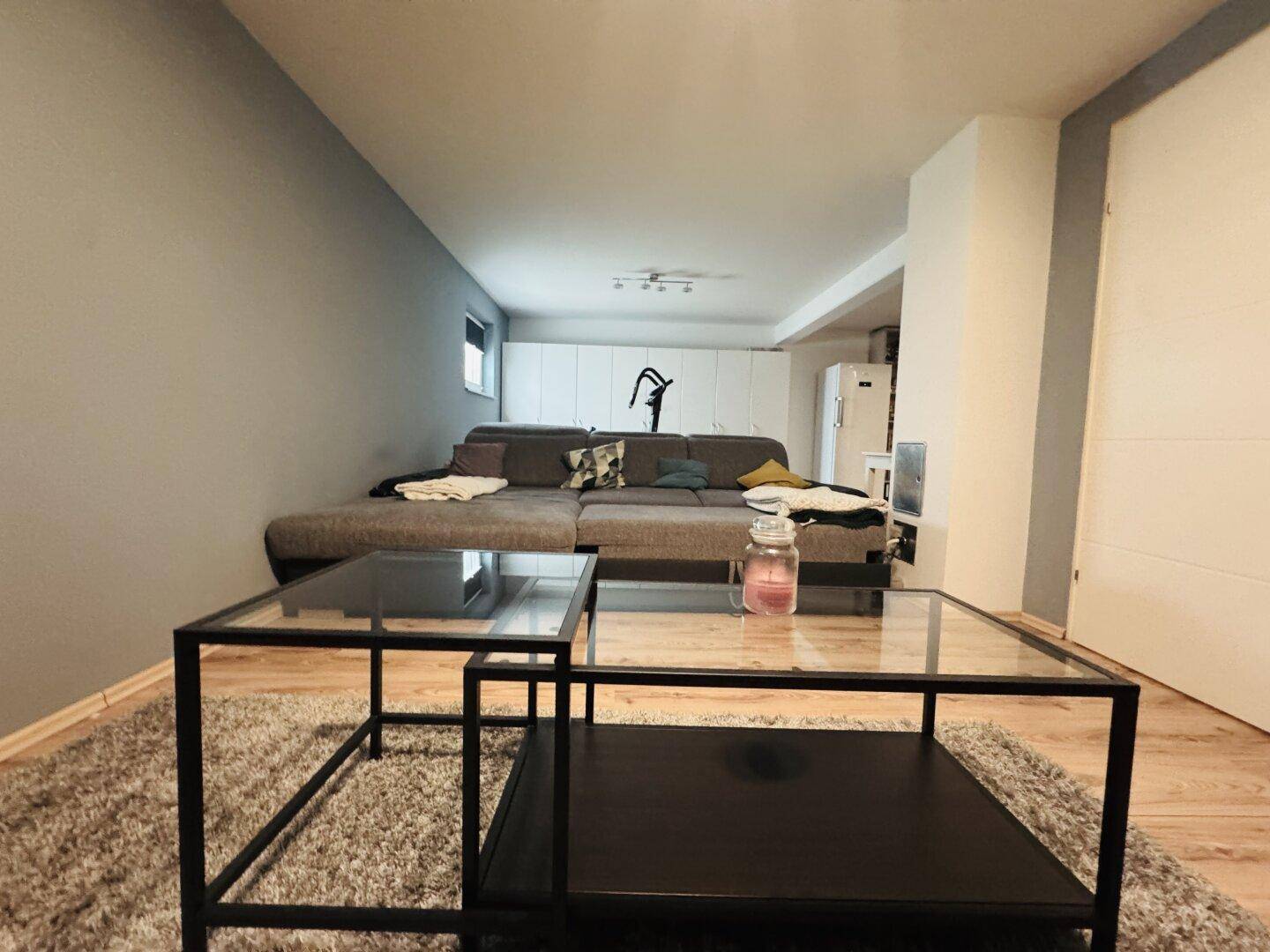 Geräumiger Medienraum im Untergeschoss mit großem Sofa und modernem Interieur.