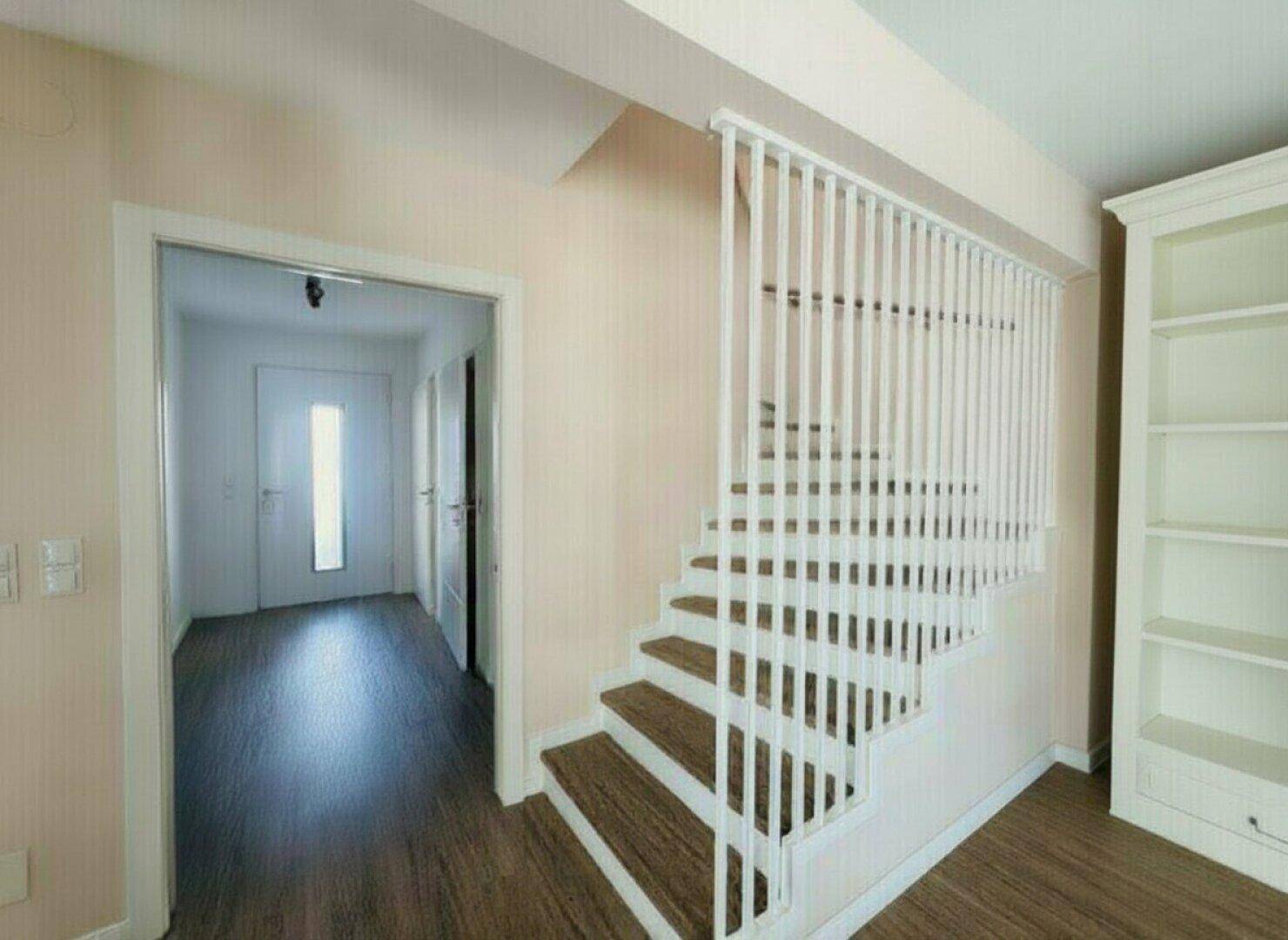Heller Eingangsbereich mit moderner Treppe und Laminatboden, der zu den oberen Etagen führt.