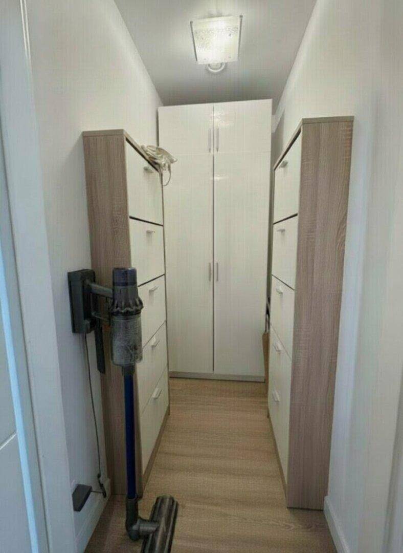 Schmaler Flur mit praktischen Schuhschränken und einem hohen Schrank für zusätzlichen Stauraum.