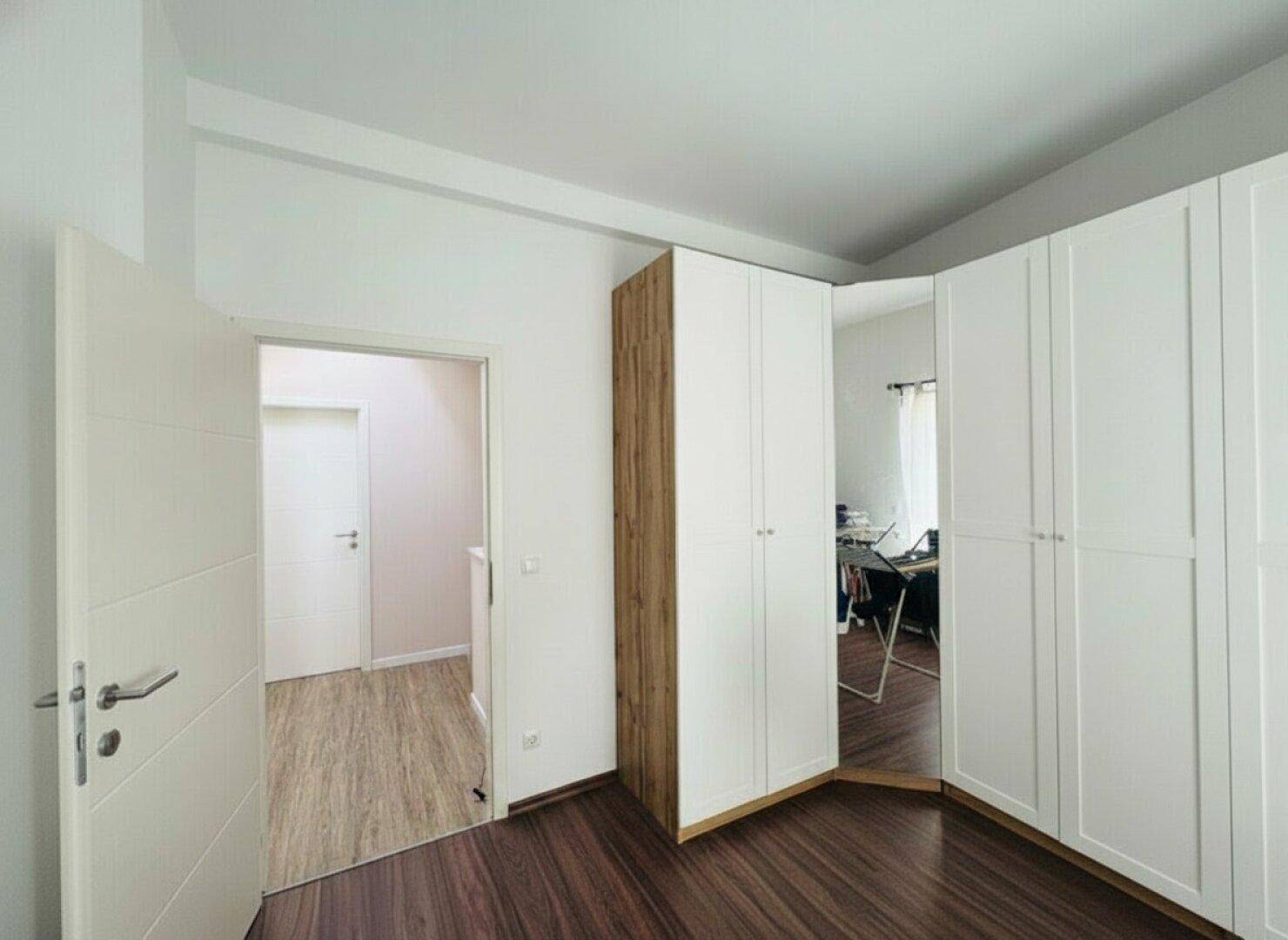 Schlafzimmer mit weißen Einbauschränken und Zugang zum Flur, hell und funktional.
