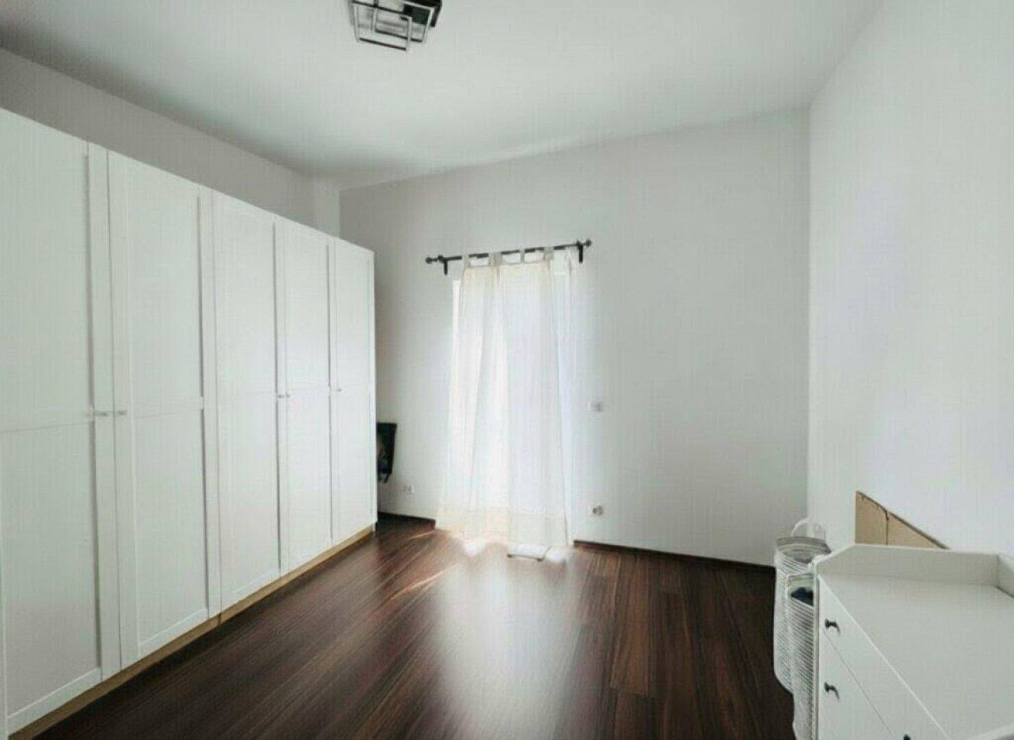 Helles Schlafzimmer mit großen weißen Kleiderschränken und dunklem Holzboden.