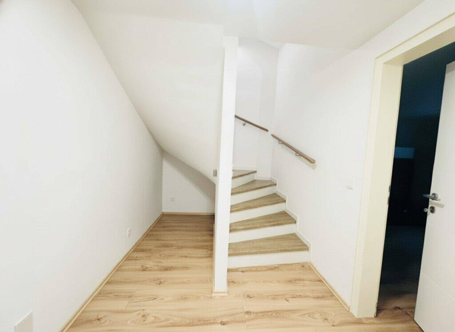 Heller Flur mit Treppe und Laminatboden, der zu den oberen Etagen führt.