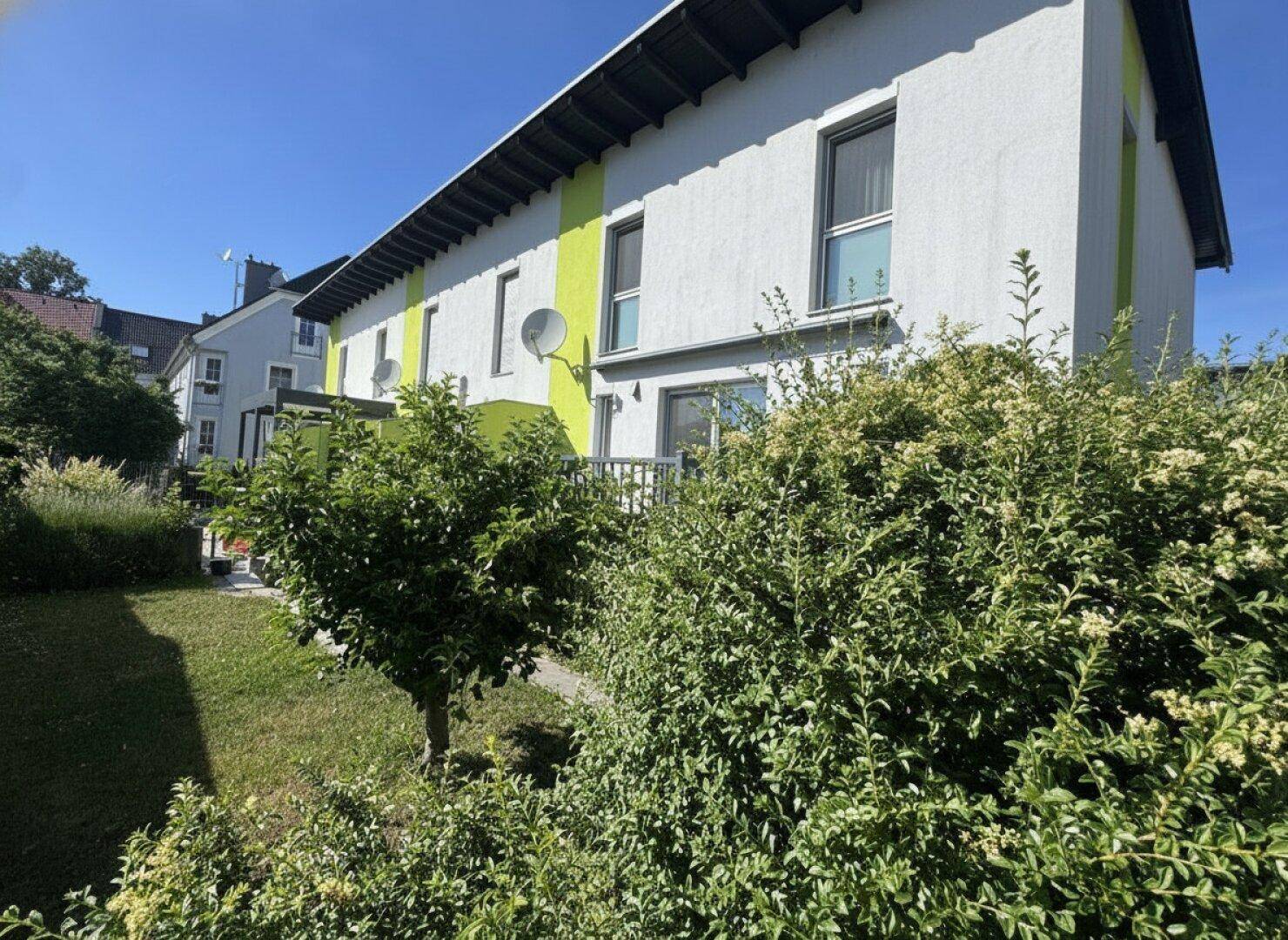 Rückseite des Hauses mit grünem Gartenbereich und Blick auf die Nachbarschaft.