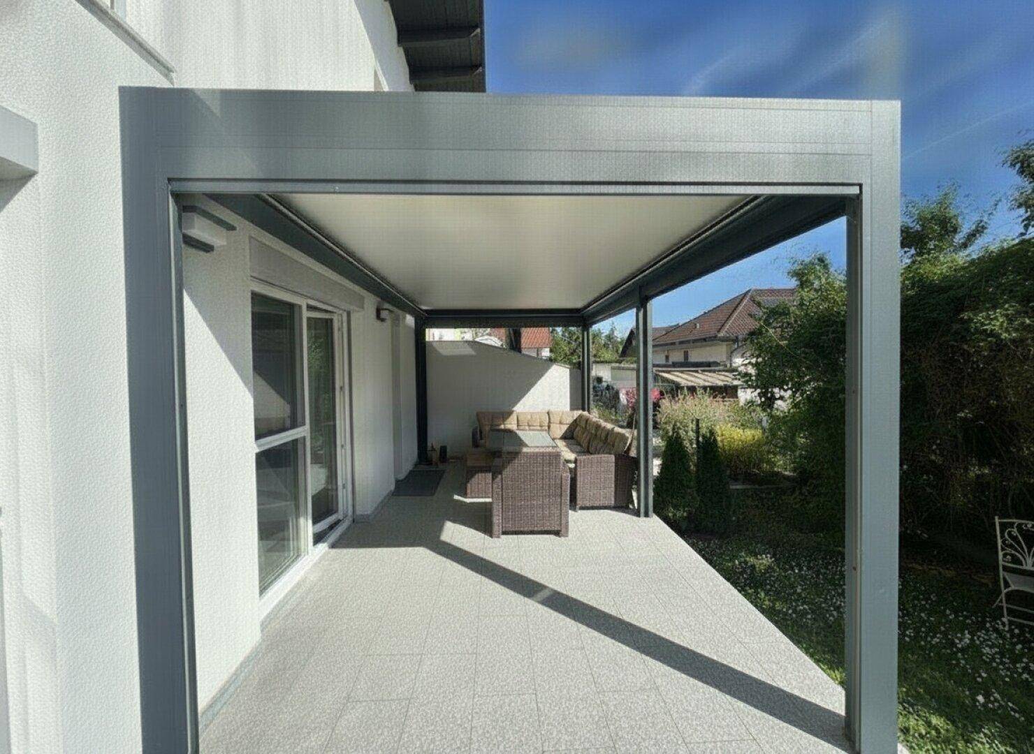 Moderne überdachte Terrasse mit bequemen Gartenmöbeln und Zugang zum Haus.
