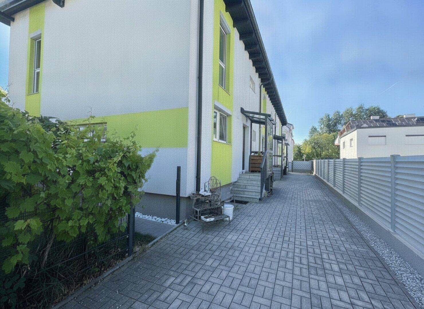 Reihenhäuser mit farbenfroher Fassade und gepflasterter Zufahrt.