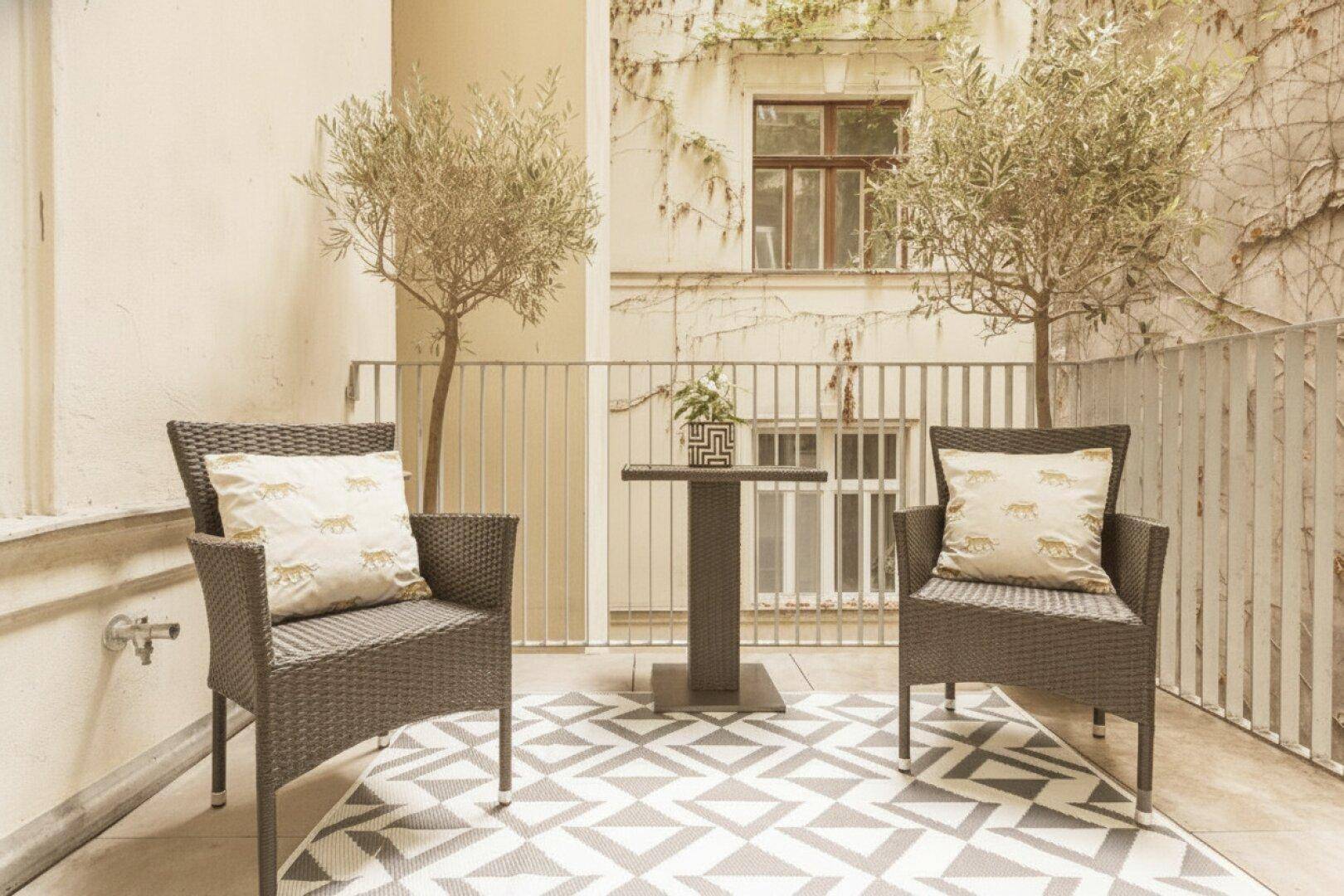 Kleiner, gemütlicher Balkon mit Sitzgelegenheiten und Blick auf den begrünten Innenhof.