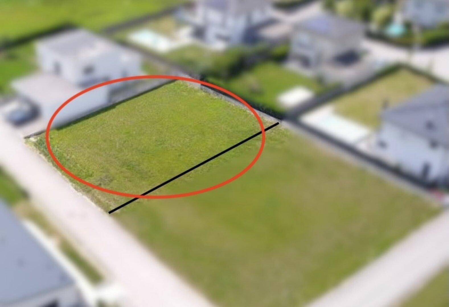 Luftaufnahme eines rechteckigen Baugrundstücks, markiert mit einem roten Kreis und einer schwarzen Linie.