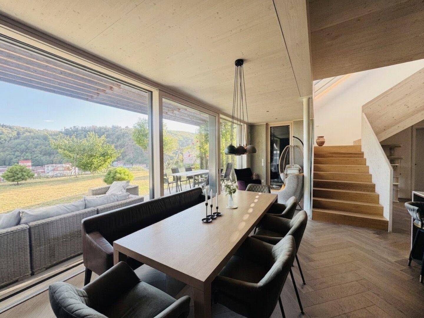 Geräumiger Wohn-Essbereich mit Holzboden, großem Esstisch und Zugang zur Terrasse mit Weitblick.