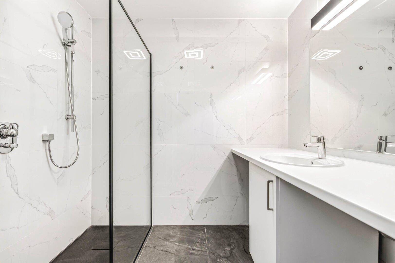 Modernes Badezimmer mit großer begehbarer Dusche, Marmorfliesen und Einzelwaschbecken.