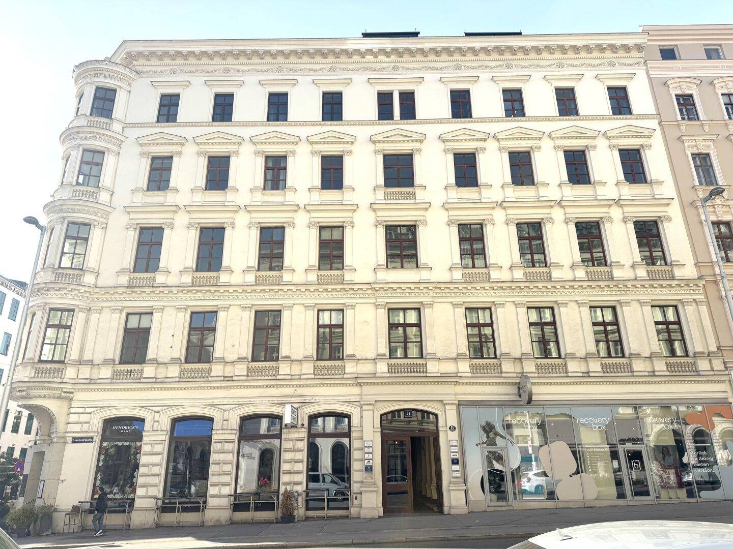 Historisches Mehrfamilienhaus mit klassischer Fassade, vielen Fenstern und Geschäften im Erdgeschoss.