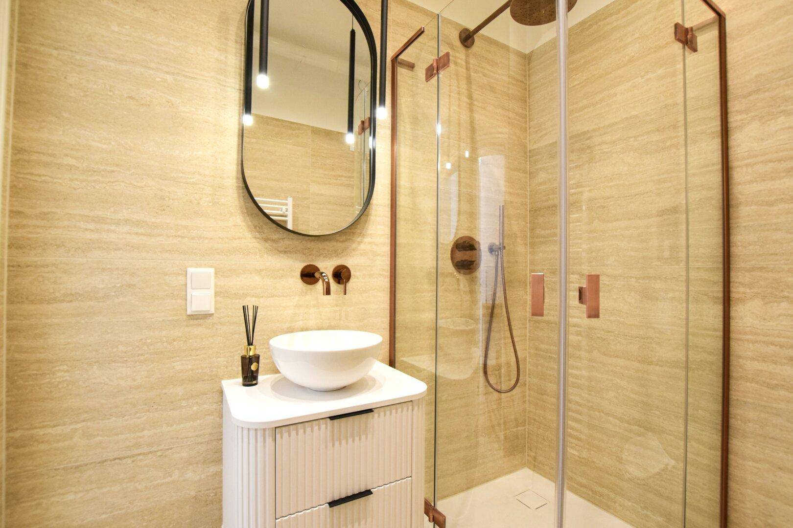 Elegantes Badezimmer mit beigefarbenen Fliesen, modernem Waschtisch und Dusche.