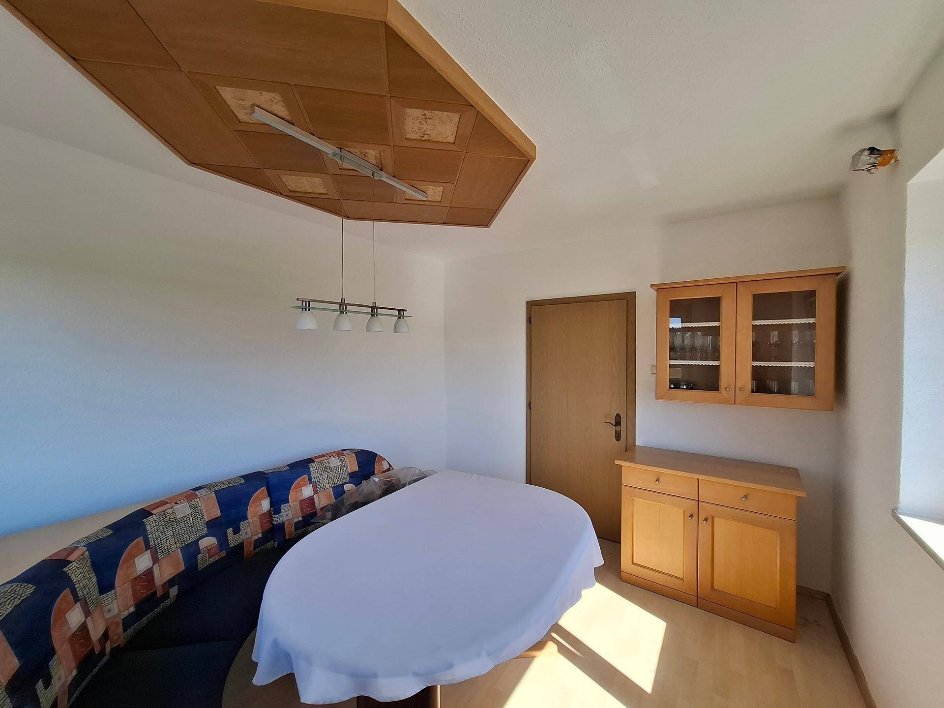 Heller Essbereich mit Eckbank, Holztisch und dekorativer Deckenverkleidung, einladend gestaltet.