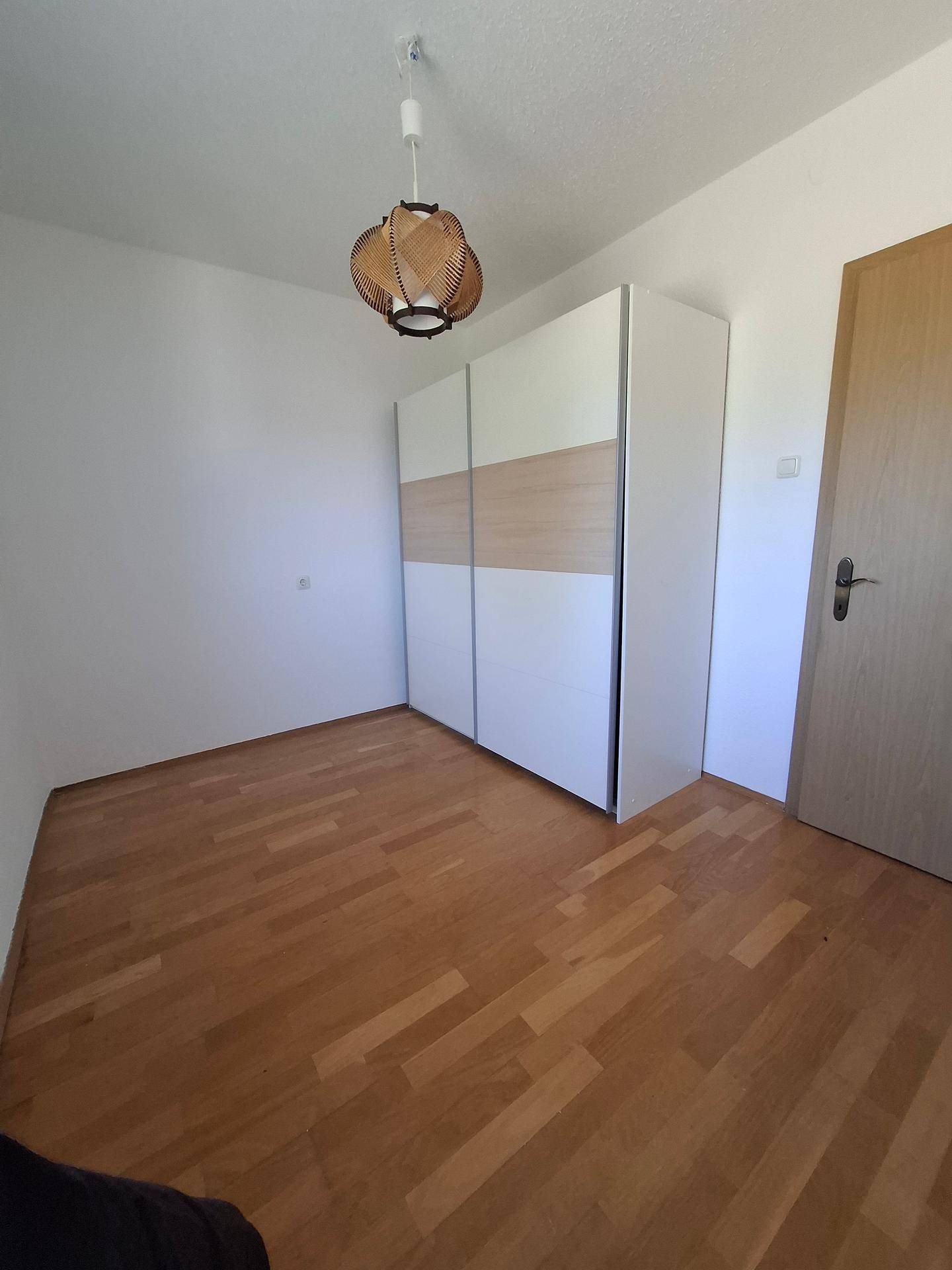 Schlafzimmer mit Holzboden und modernem Kleiderschrank, hell und funktional.