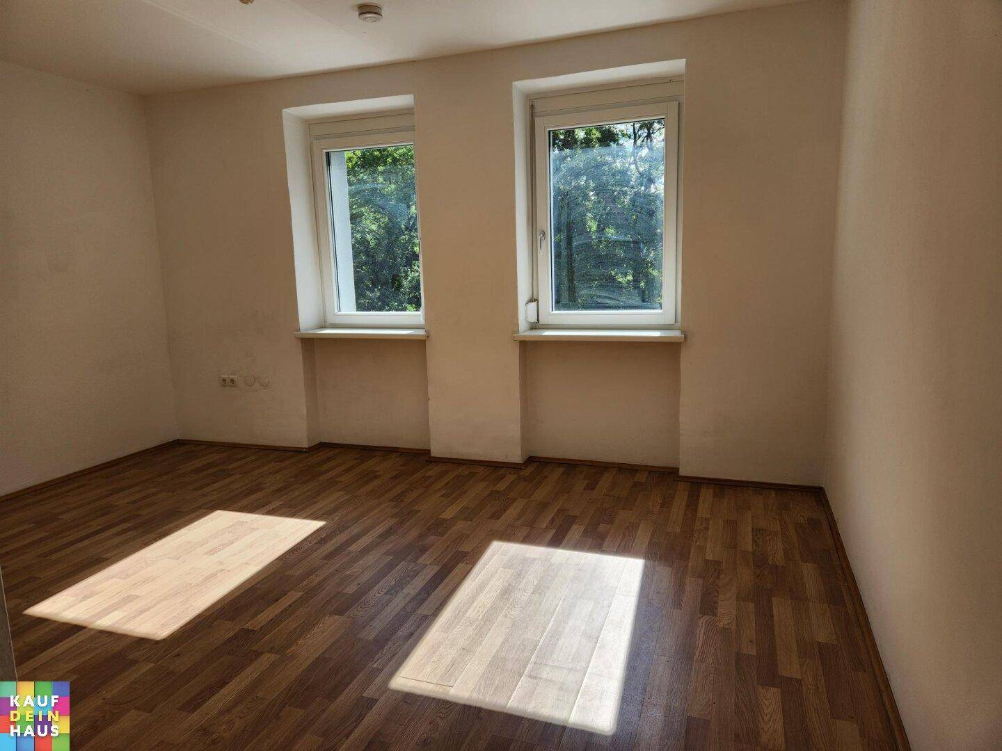 Sonniges Zimmer mit Laminatboden und hellen Wänden, ideal als Schlaf- oder Arbeitszimmer.