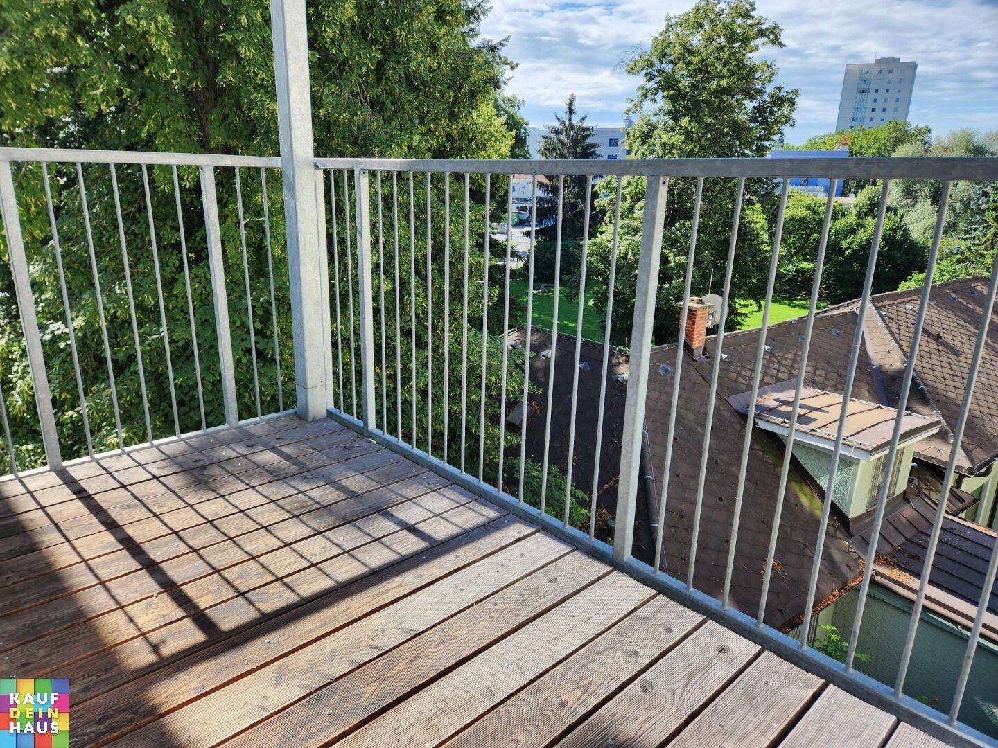 Geräumiger Balkon mit Holzboden und Metallgeländer, ideal für entspannte Stunden im Freien.