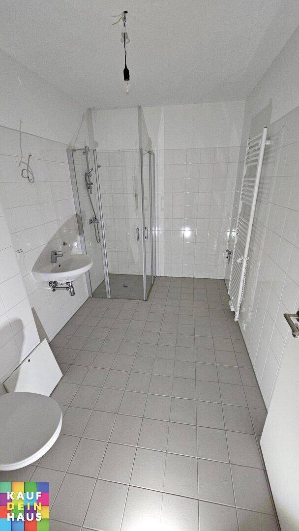 Helles Badezimmer mit Duschkabine, WC, Waschbecken und weißen Wandfliesen.