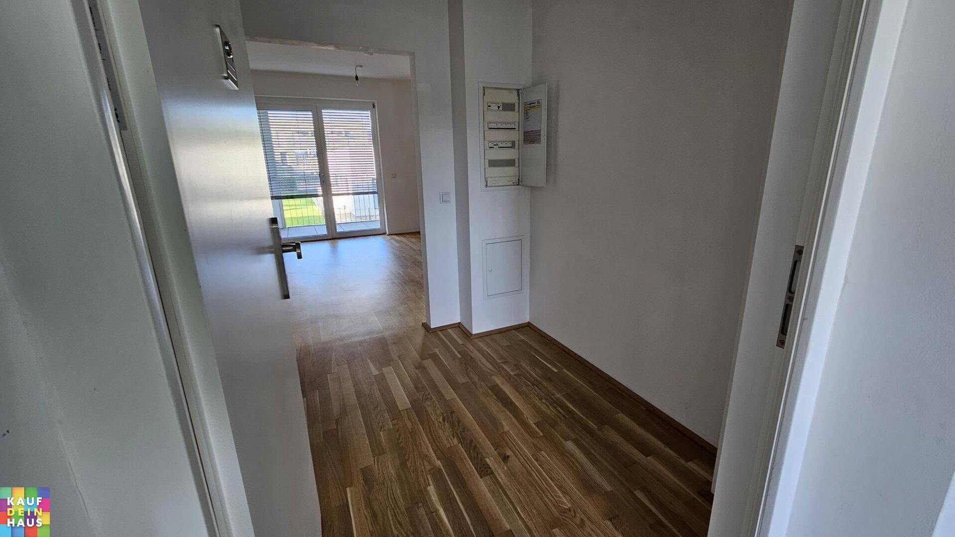 Heller Eingangsbereich mit Holzboden und Blick in den offenen Wohnbereich.