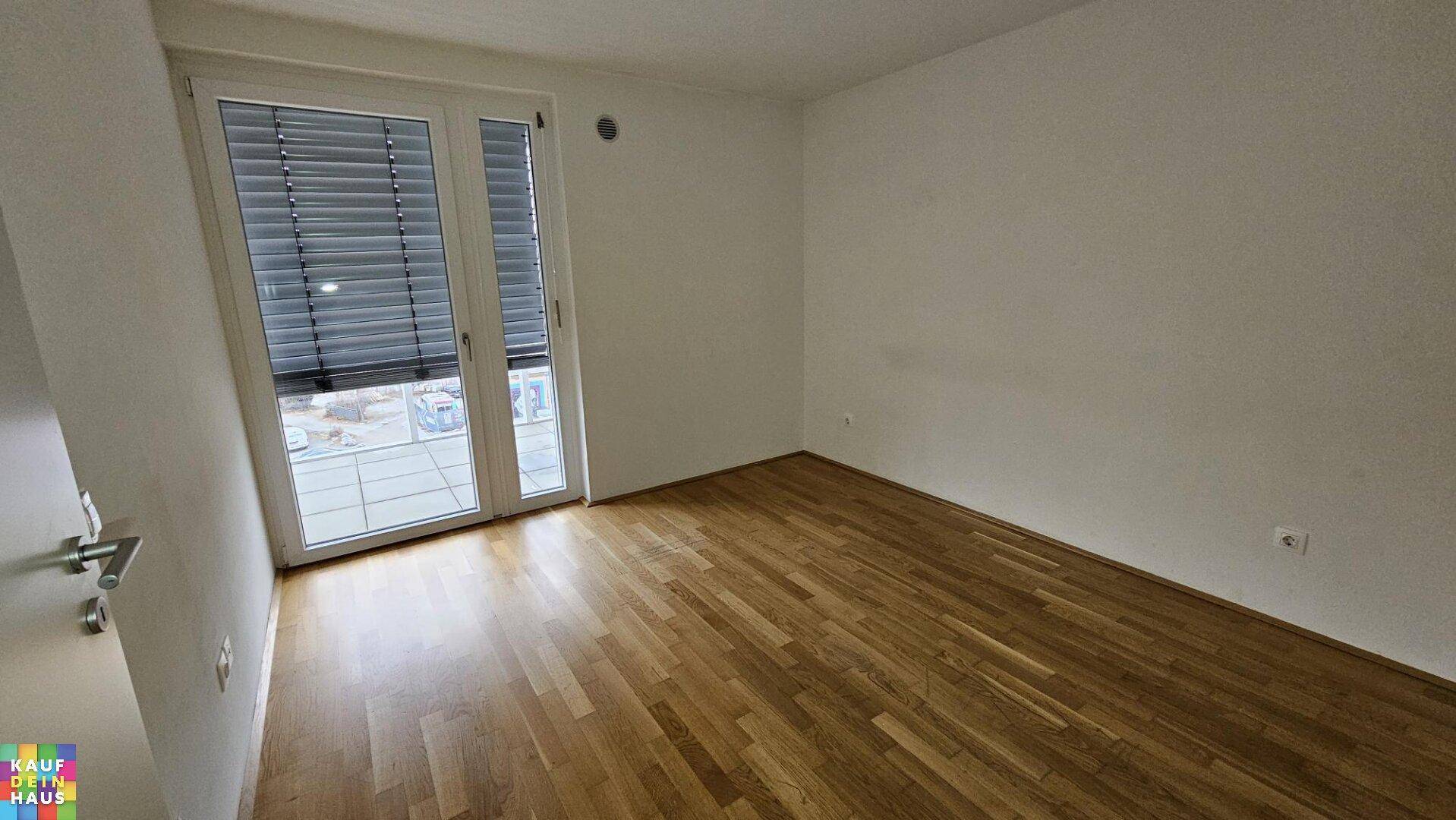 Helles Schlafzimmer mit Parkettboden und direktem Zugang zu einem Balkon oder einer Loggia.