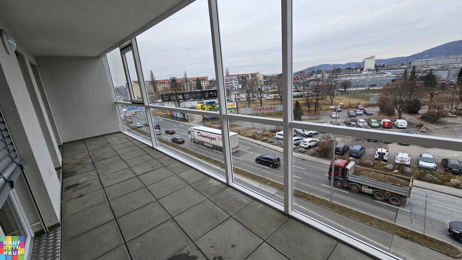 Verglaste Loggia mit weitem Blick auf die Stadt und die belebte Straße.
