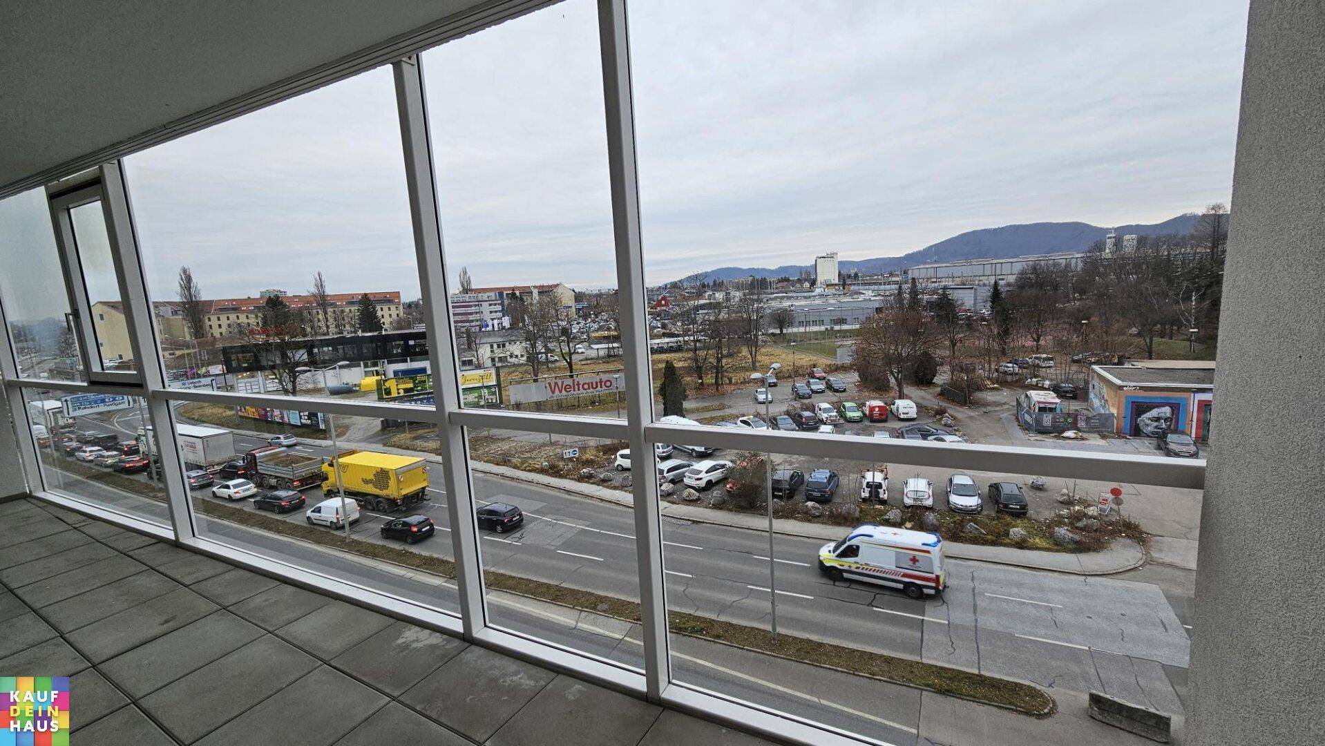 Panoramablick von der Loggia über die Stadtlandschaft mit Bergen im Hintergrund.
