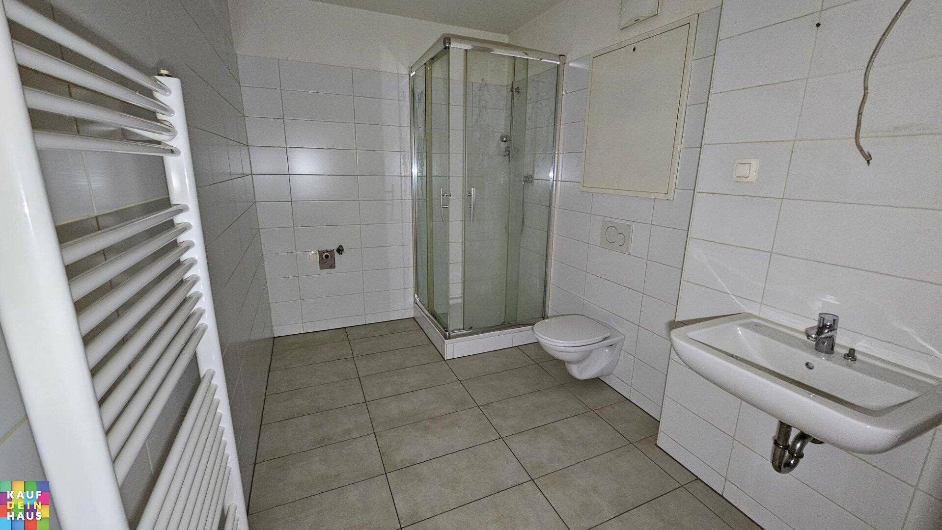 Modernes Badezimmer mit Duschkabine, WC, Waschbecken und Handtuchheizkörper.