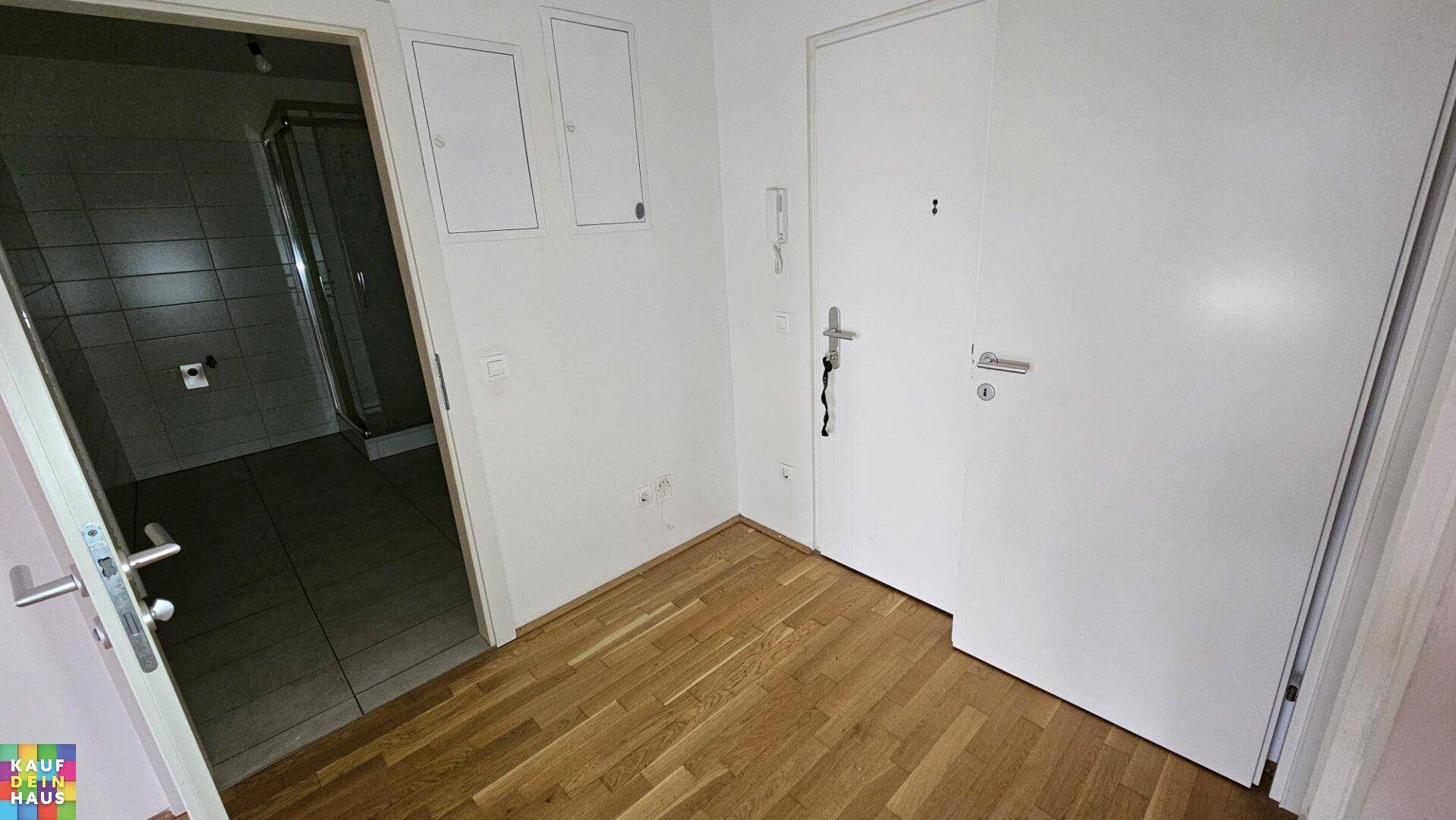 Heller Flur mit Parkettboden und Zugang zum Badezimmer, sauber und funktional.