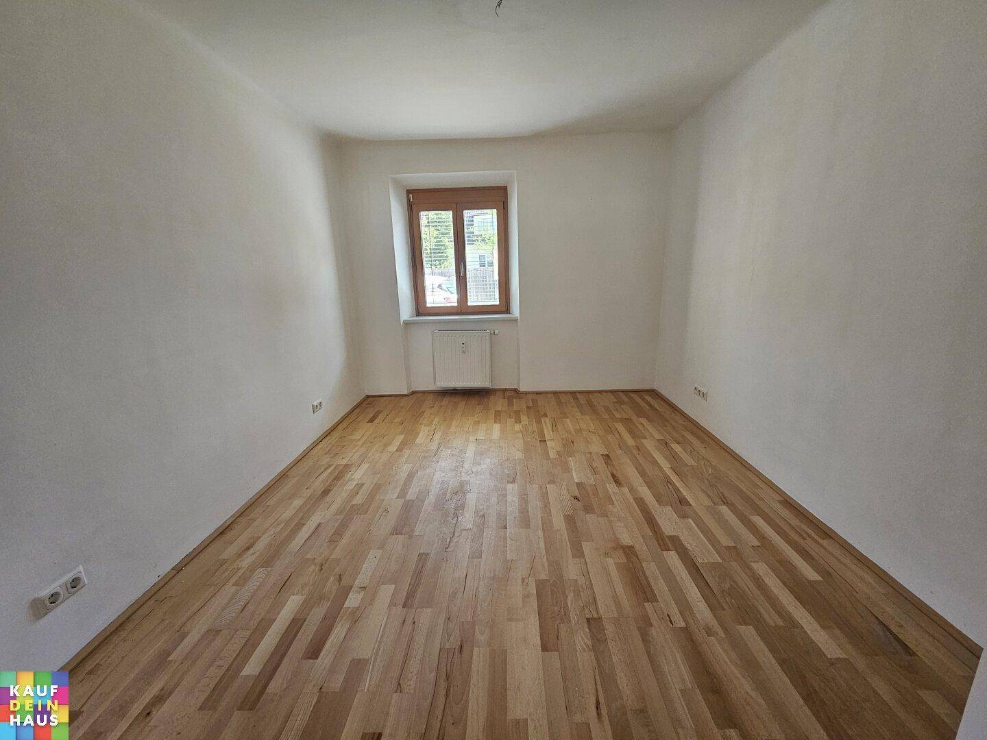 Heller, leerer Raum mit Holzboden und einem Fenster, bereit zur individuellen Gestaltung.