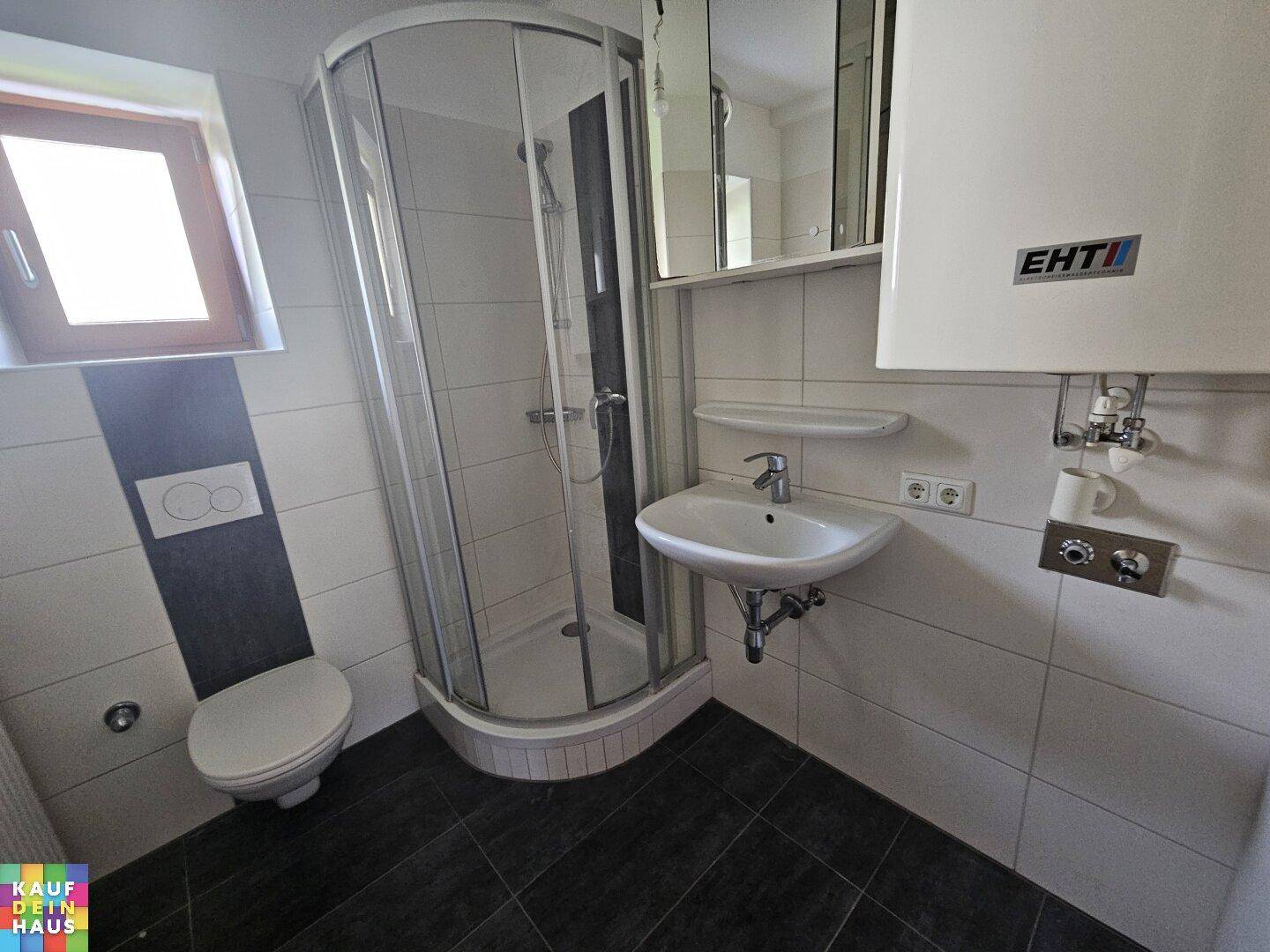 Modernes Badezimmer mit Duschkabine, WC, Waschbecken und einem Fenster.