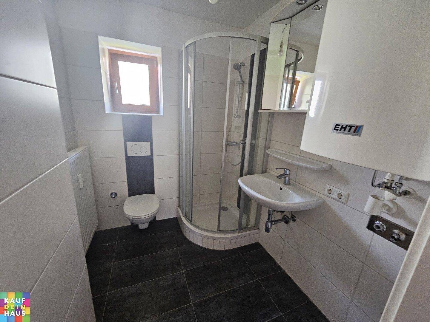 Helles Badezimmer mit Duschkabine, WC, Waschbecken und einem Fenster für Tageslicht.