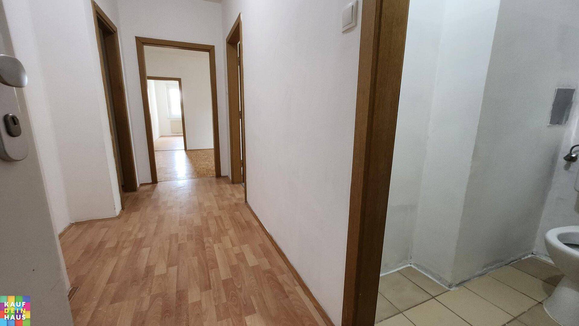 Heller Flur mit Laminatboden und mehreren Türen, der zu verschiedenen Räumen führt.