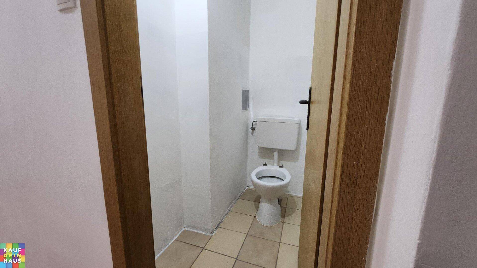 Kleines separates WC mit Fliesenboden und einfacher Ausstattung, ideal für Gäste.