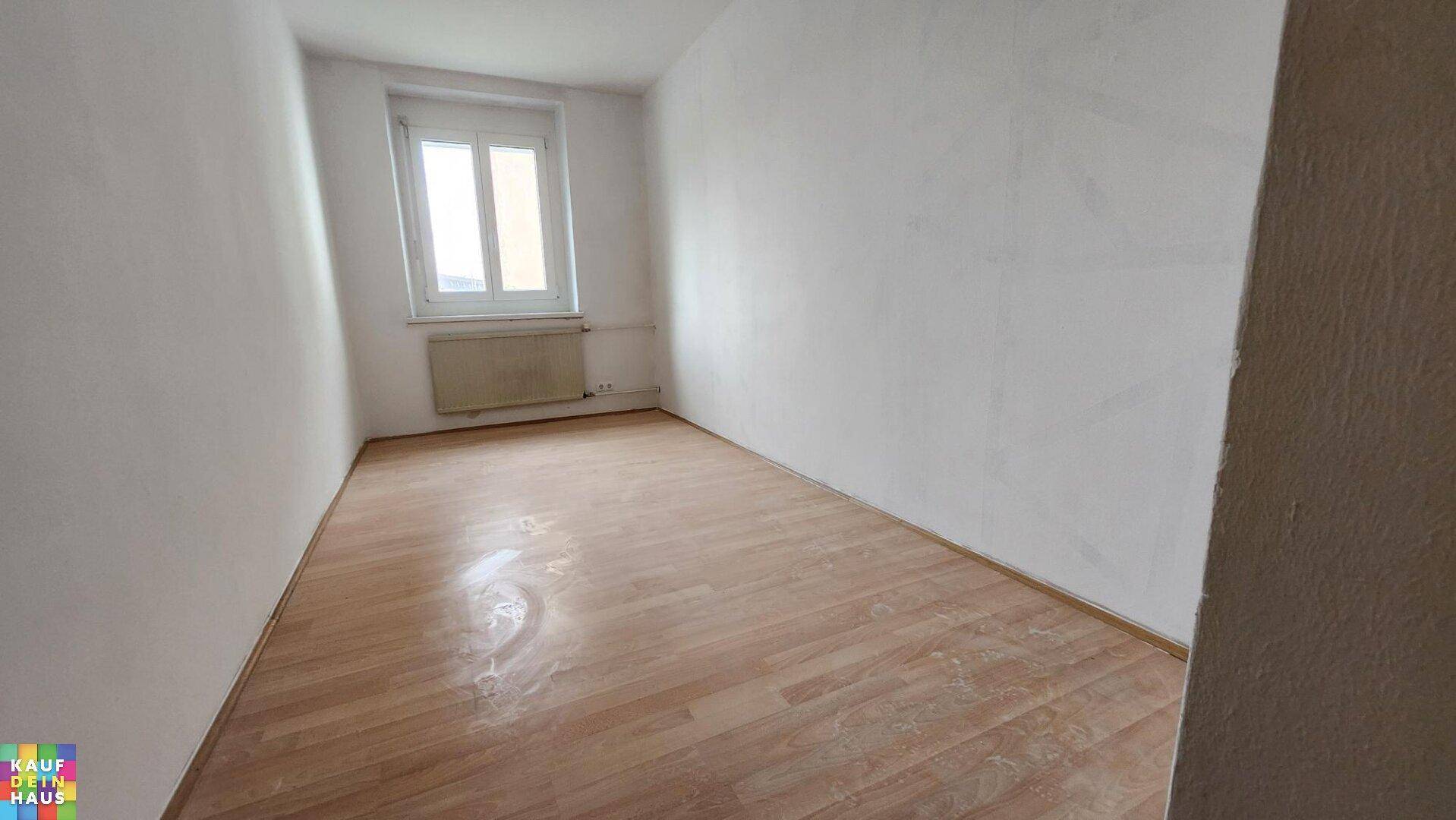 Geräumiges Zimmer mit Laminatboden und Fenster, bietet viel Platz für individuelle Gestaltung.