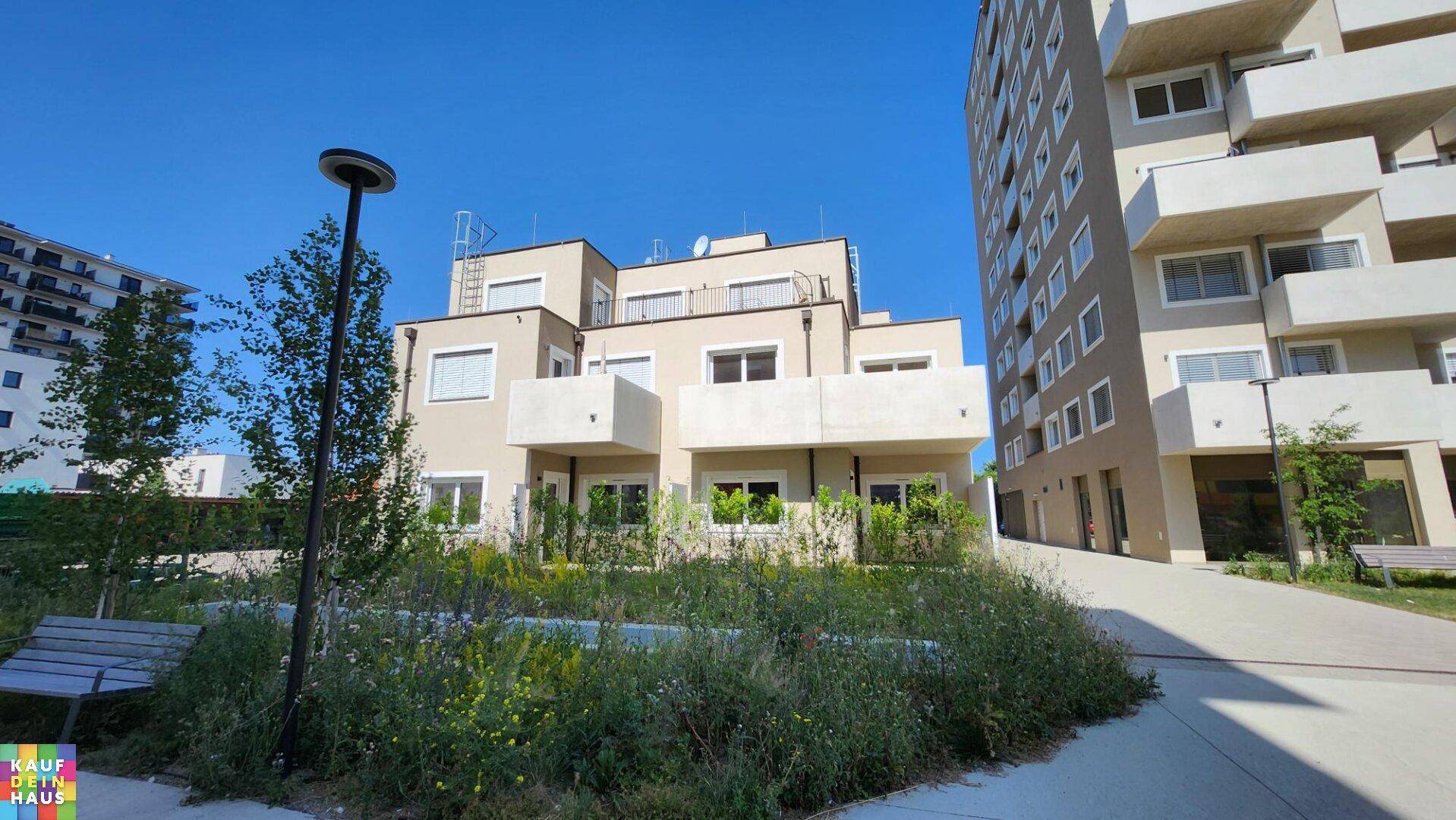 Ansicht eines modernen Wohnkomplexes mit gepflegten Grünflächen und Wegen.
