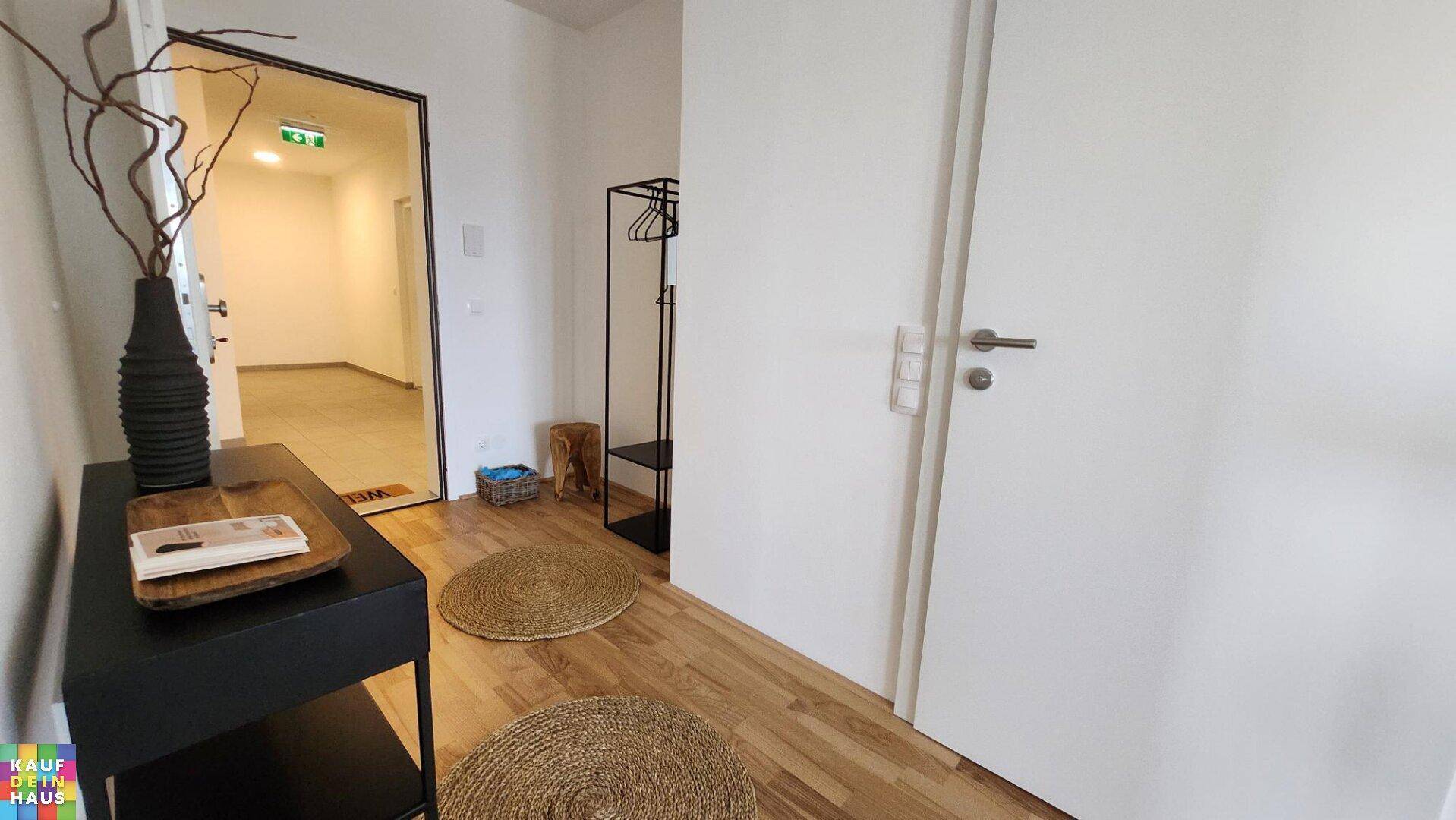 Eingangsbereich mit Holzboden, moderner Dekoration und weißer Tür.