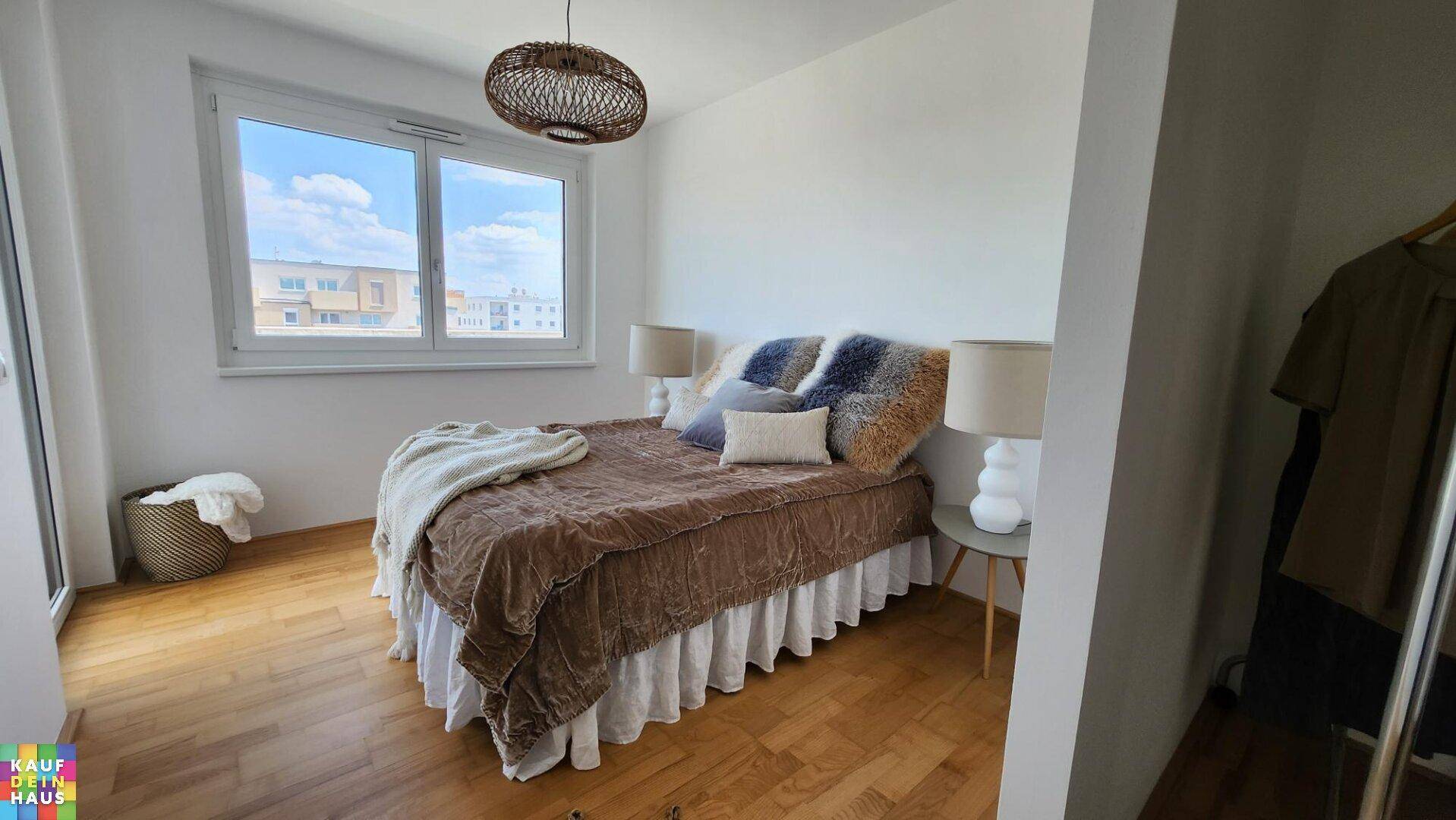 Helles Schlafzimmer mit Holzboden, großem Fenster und gemütlichem Bett.