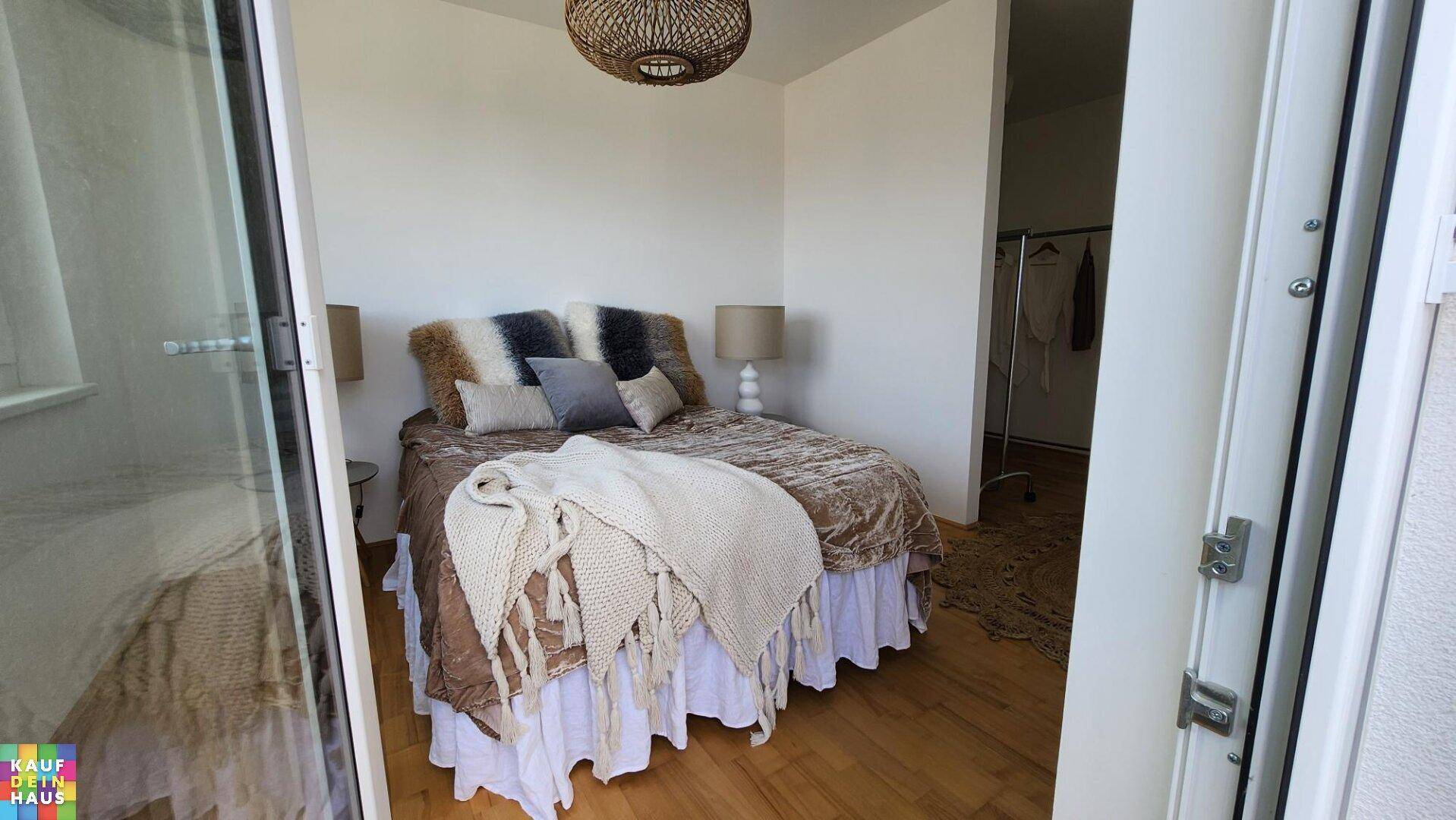 Schlafzimmer mit Holzboden, Zugang zum Balkon und gemütlicher Einrichtung.