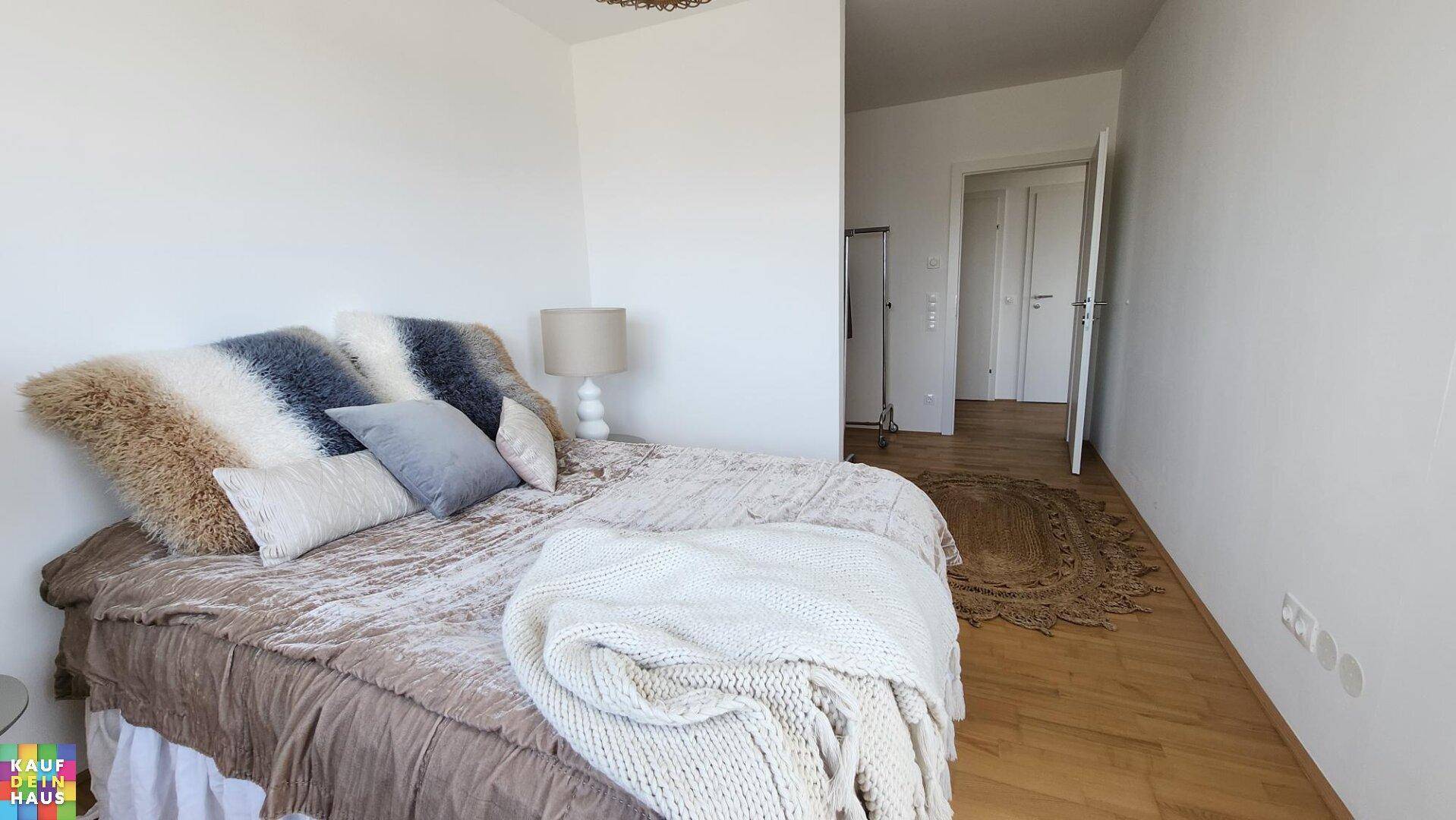 Schlafzimmer mit Holzboden, weiß gestrichenen Wänden und moderner Einrichtung.