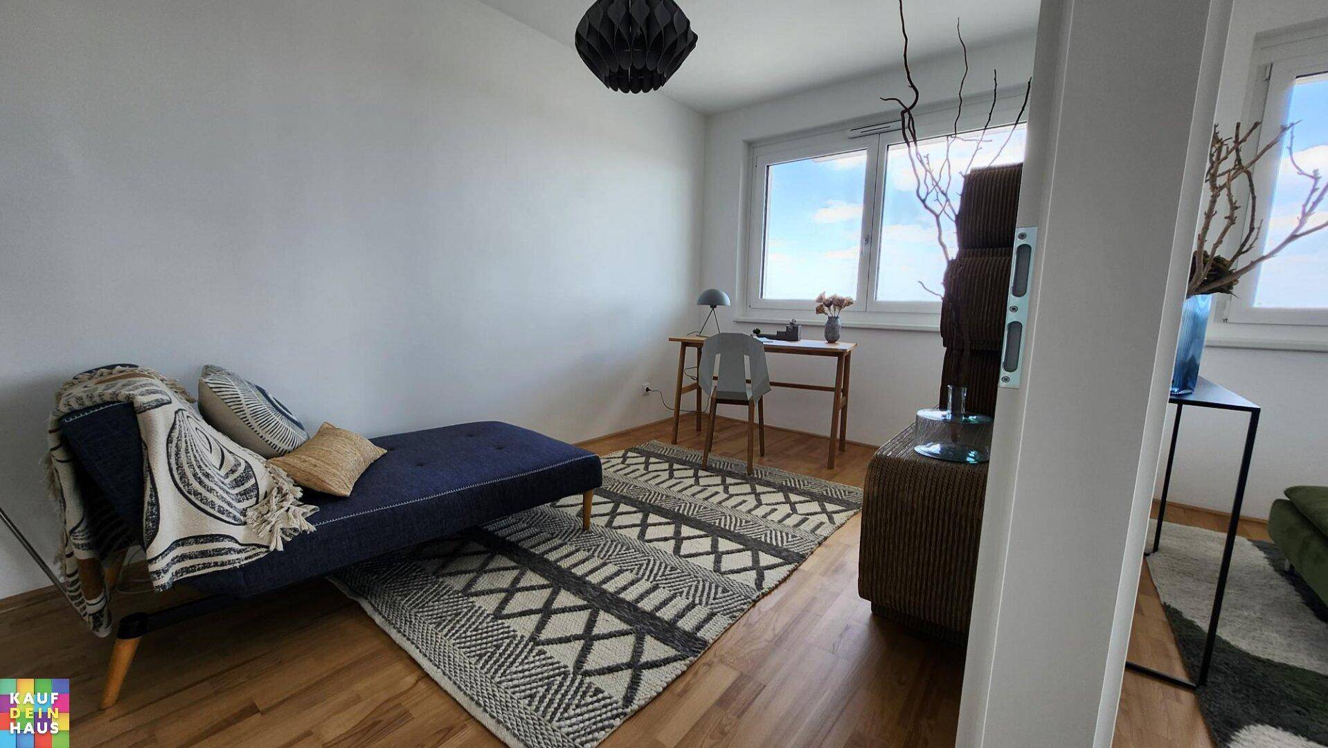 Helles Arbeitszimmer mit Holzboden, großem Fenster und minimalistischer Einrichtung.