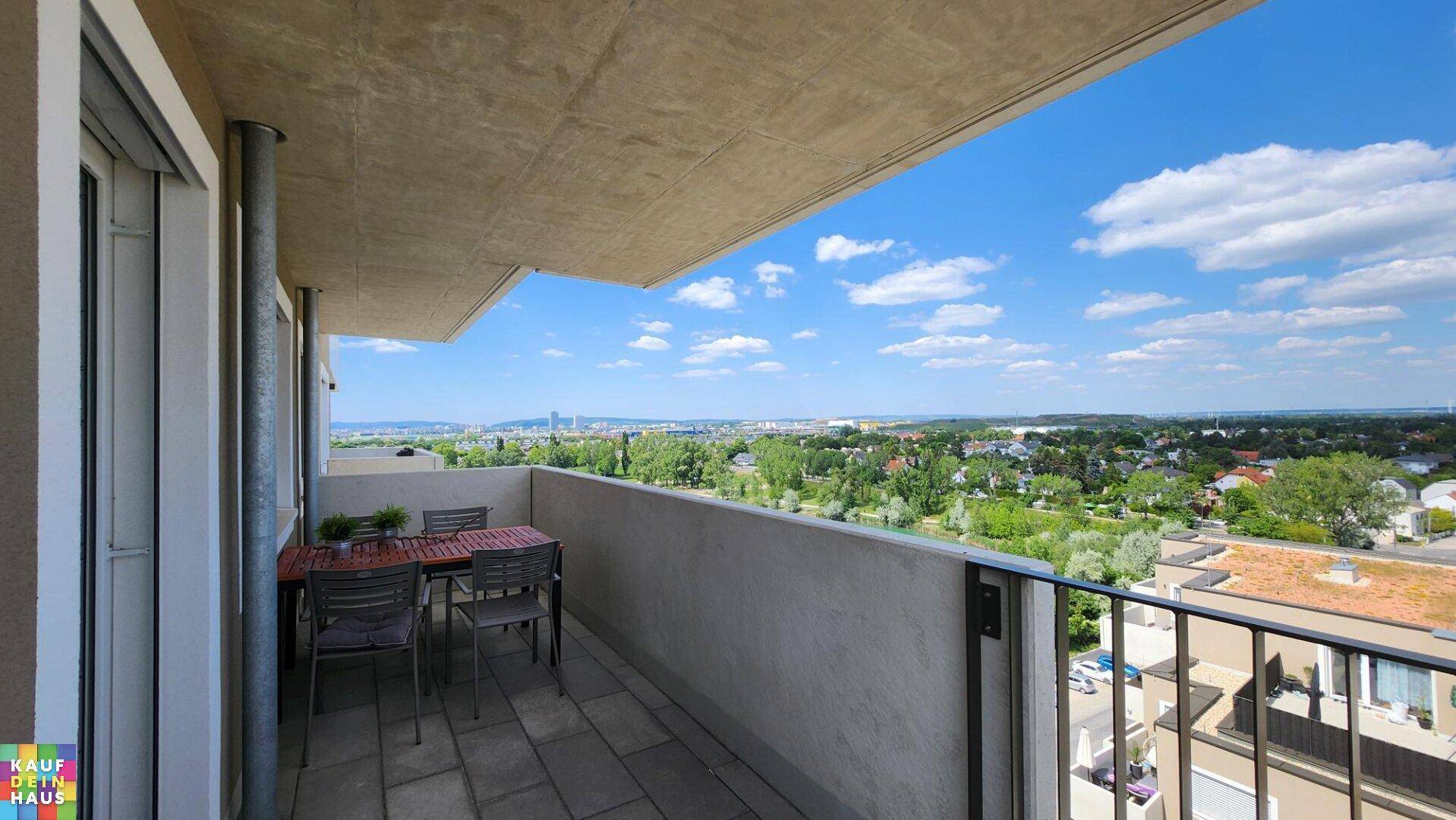 Geräumiger Balkon mit Esstisch und weitem Blick über die Stadt und Landschaft.