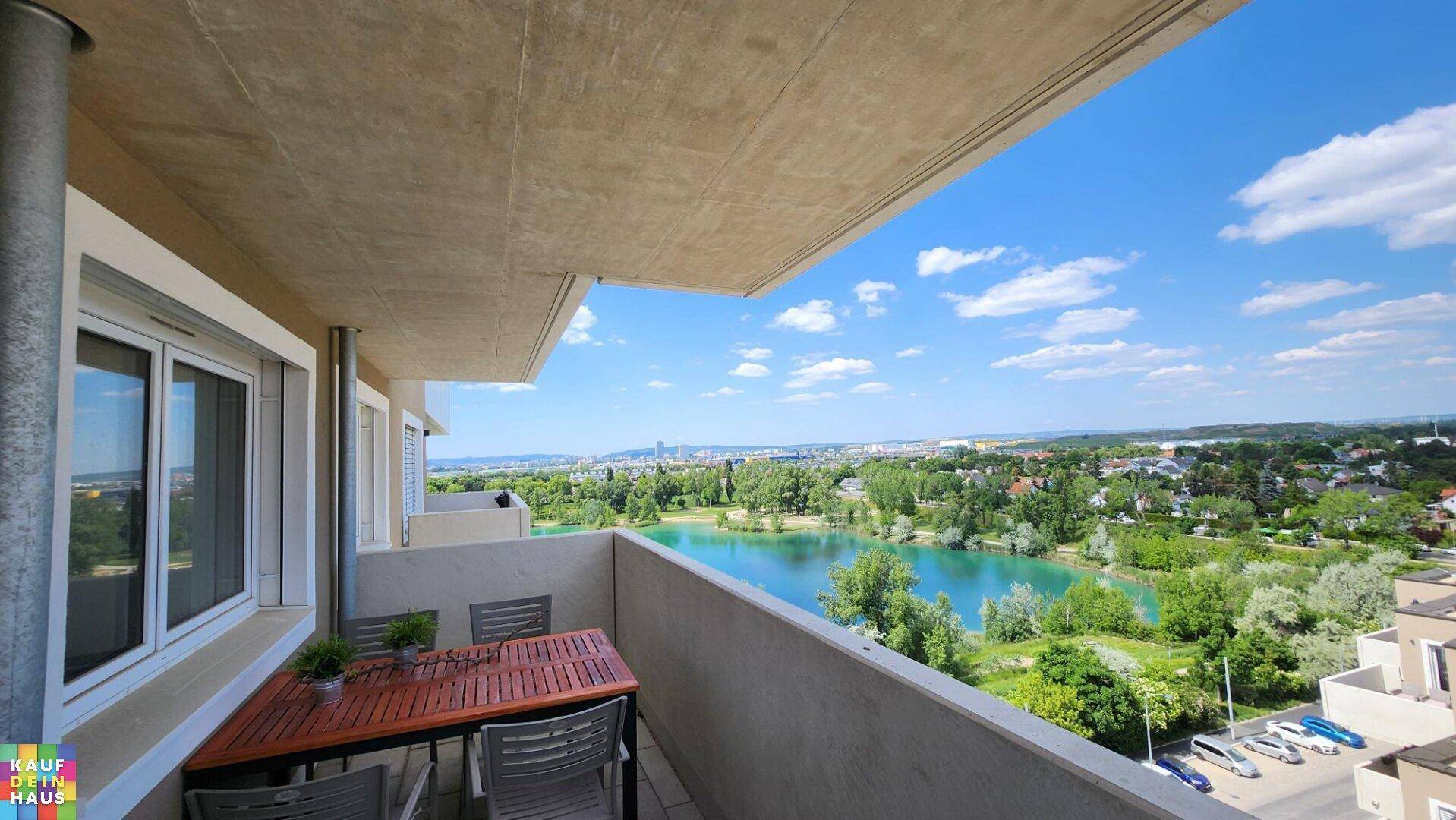 Balkon mit Esstisch und Panoramablick auf einen See und die umliegende Stadt.
